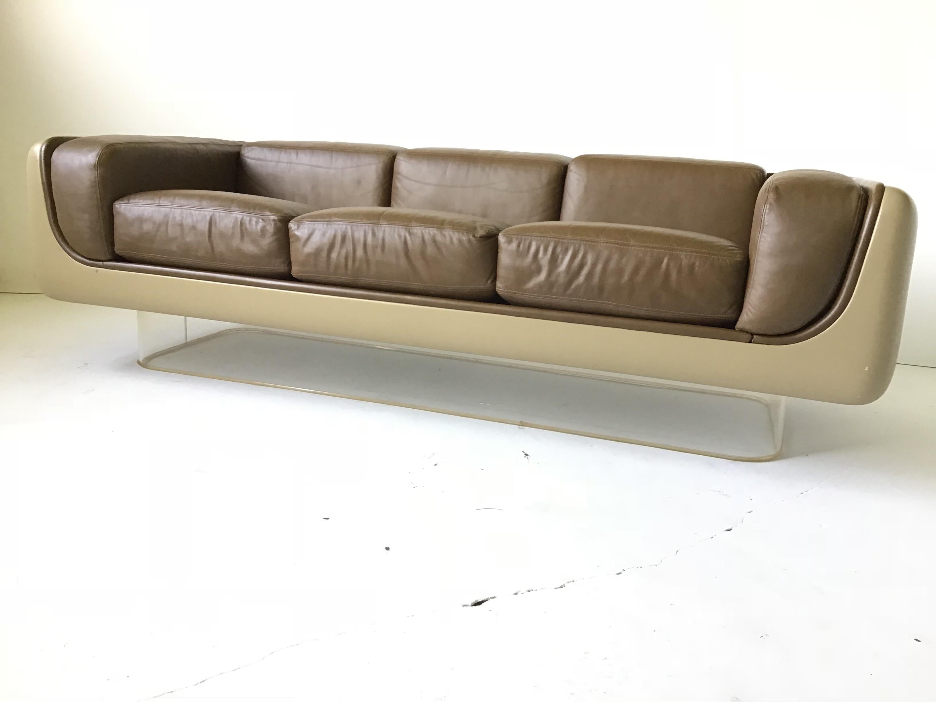 This is the most fantastic version of this sofa I have ever in original condition. It is a design by William Andrus for Steelcase furniture. It retains its orig chocolate leather cushions. The fiberglass is beige and it is on a Lucite base. This