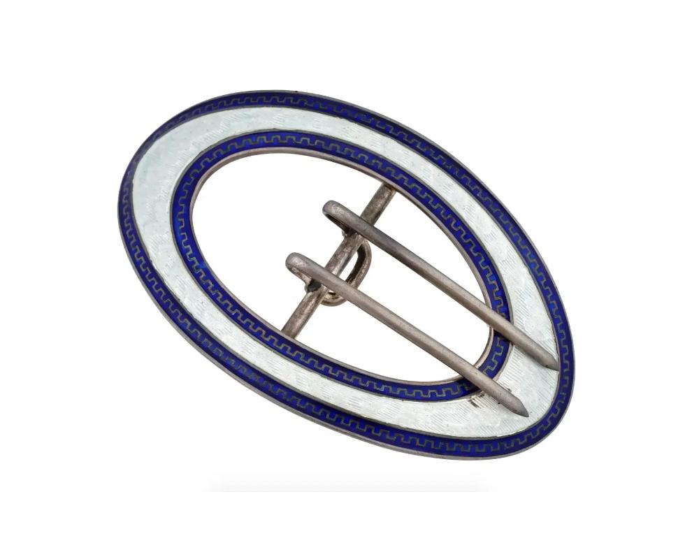 An antique sterling silver sash brooch with two prongs by William B. Kerr and Co., an American company from Newark, NJ active from 1855 to 1927. Blue and white guilloche enameled piece with ornamental decor. This type of brooch was often worn in