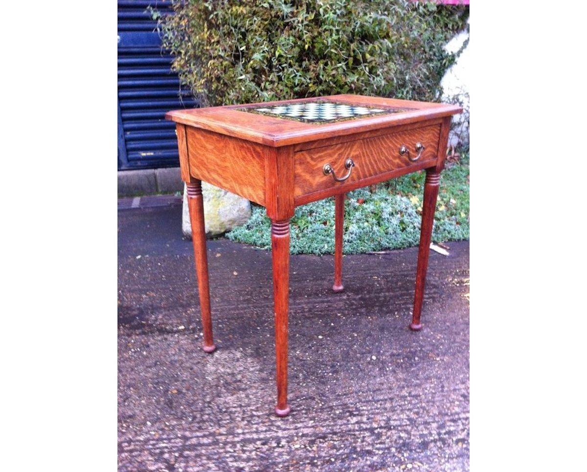 William Birch for Liberty & Co.
A good quality Arts & Crafts oak chess table with hand painted glass to the underside of the chess playing board, with different marble effects and decorative floral boarders, a storage drawer below with the original