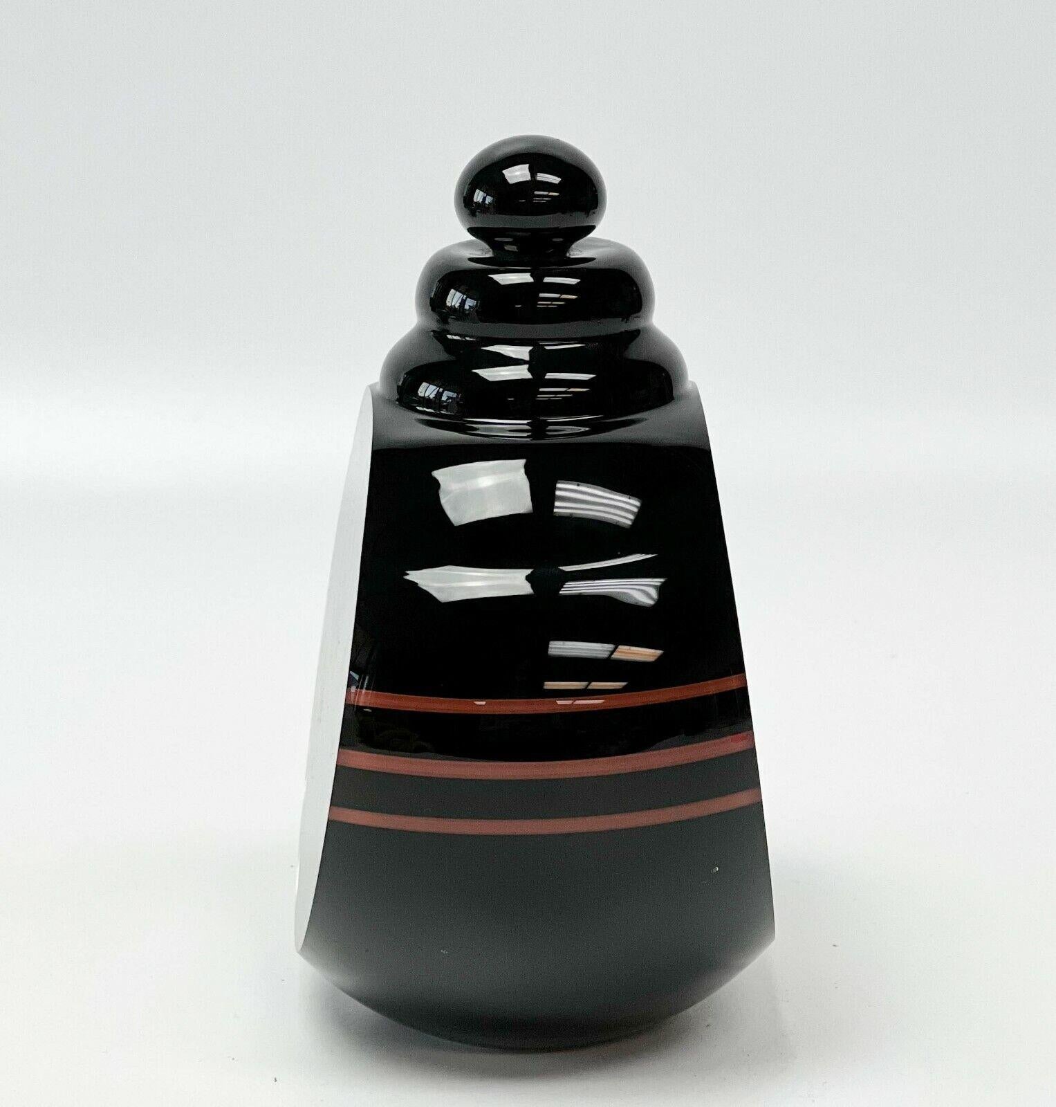 William Carlson Art Glass hand blown center perfume bottle with stopper, signed.

Black colored glass with cut shoulders, red band decoration and green with controlled bubbles to the interior. Etched William Carlson 1978 into the