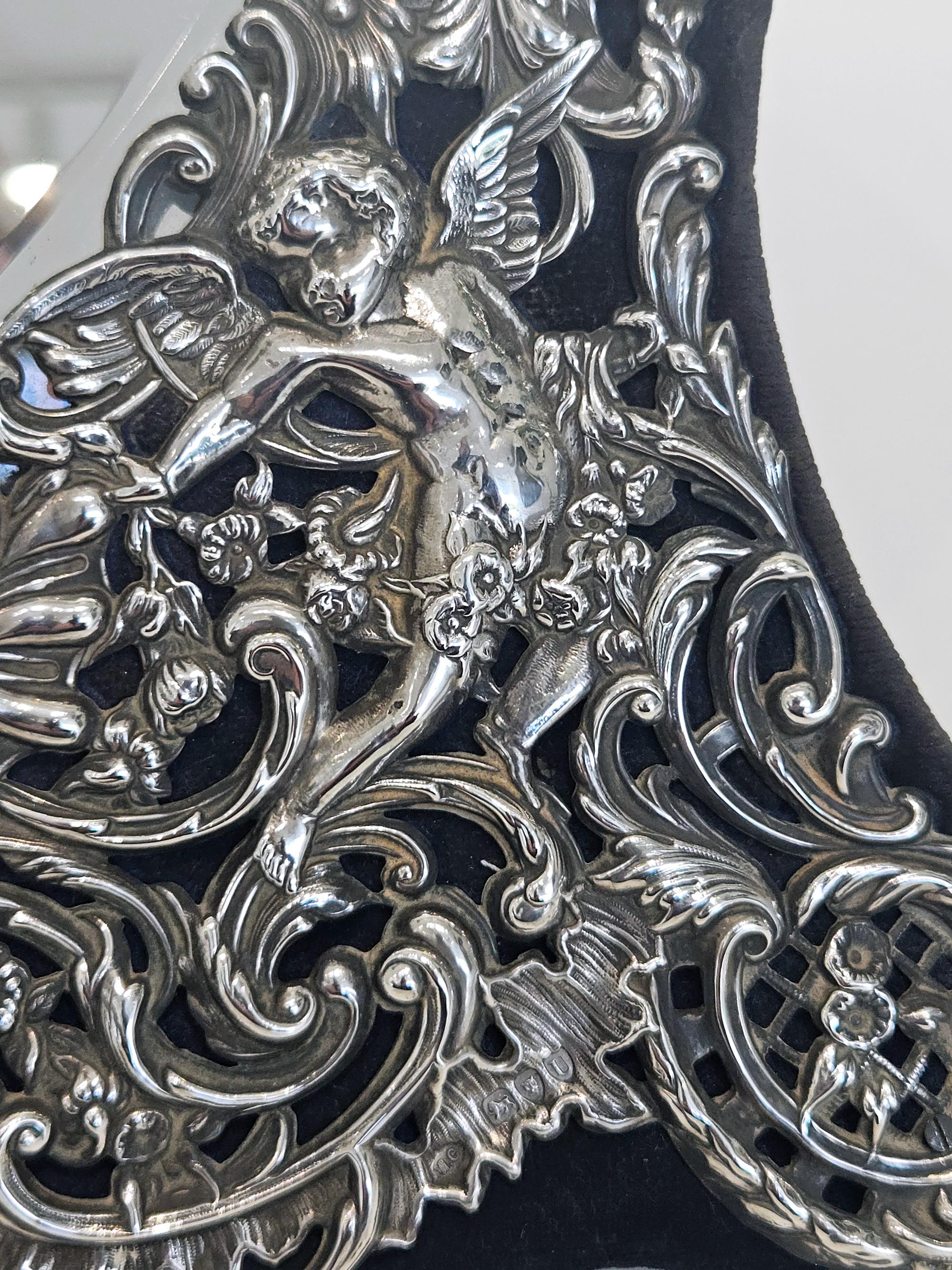 Bellissimo e molto decorativo specchio da toeletta in argento a forma di cuore di grandi dimensioni realizzato da William Comyns di Londra nel 1895. 

Lo specchio ha un'elaborata faccia in argento massiccio repousé a scorrimento con un doccione