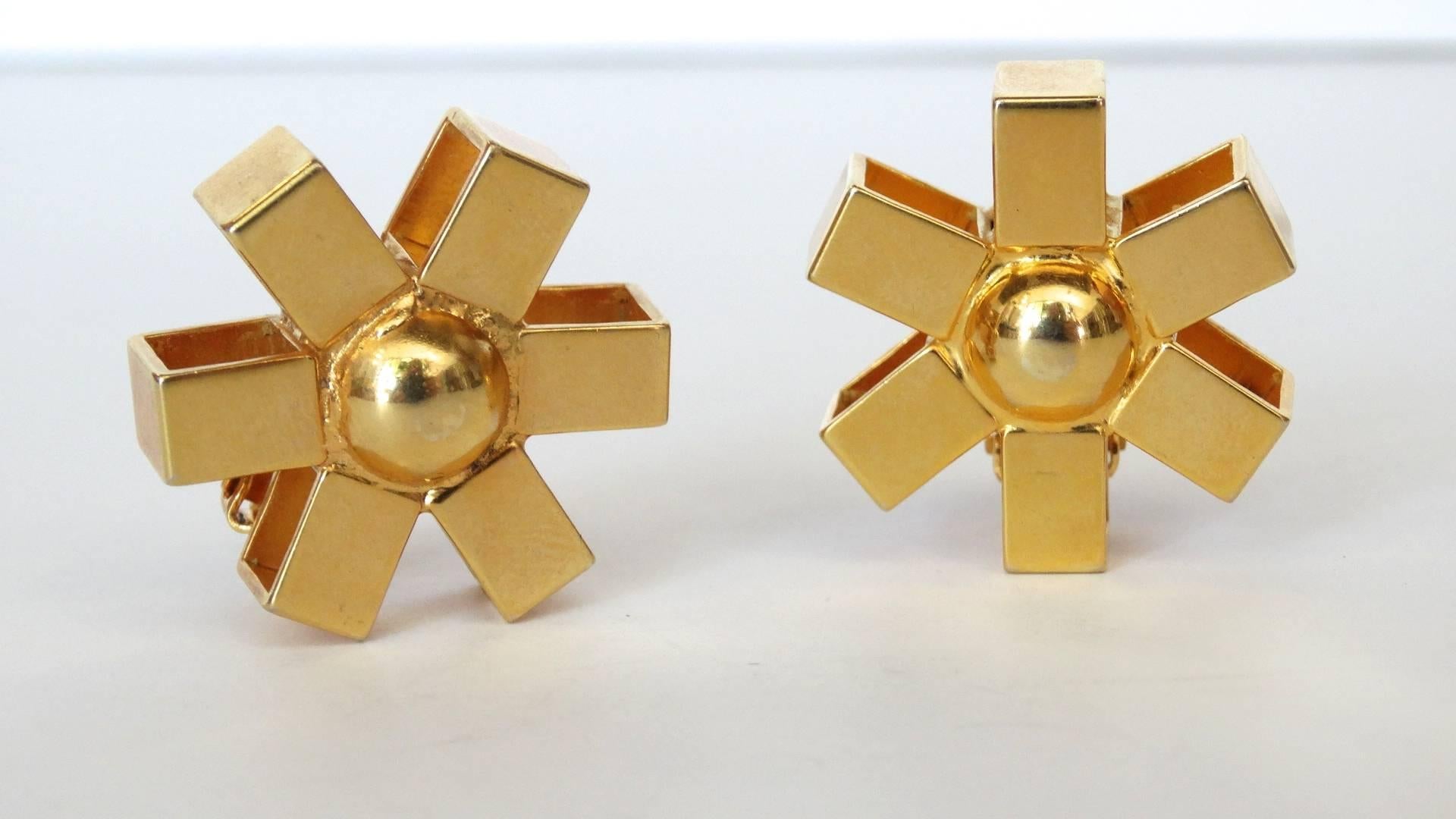 The chicest pair of gold asterisk clip on earrings from jewelry designer William De Lillo! Two asterisk style earrings cast from a brilliant gold metal, with a rounded dome in the middle. Clip on backs. Signed on each of the backs. 