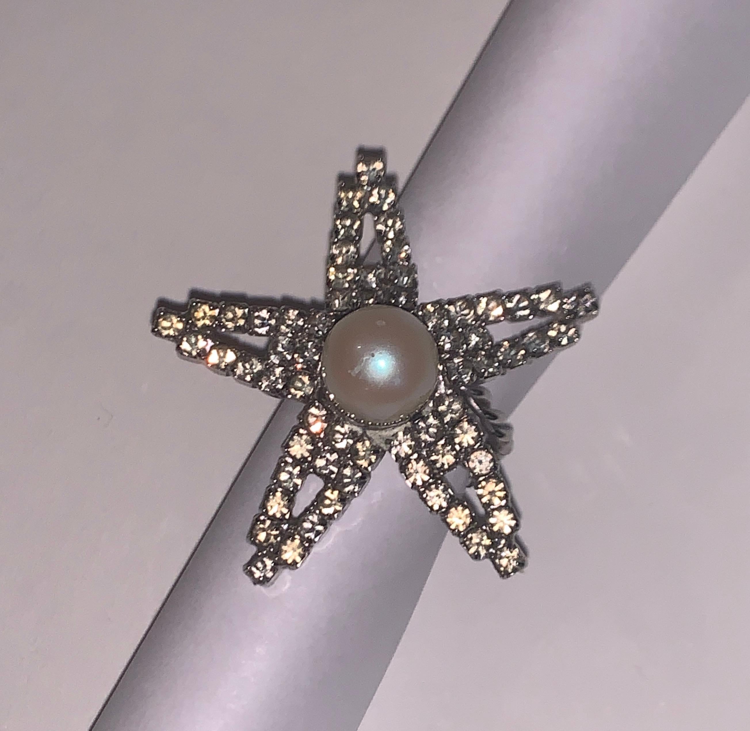 William de Lillo vintage 1970s silver rhinestone star shaped statement cocktail ring with large faux pearl center. 

Signed de Lillo at back.

Measures approximately 1 1/2