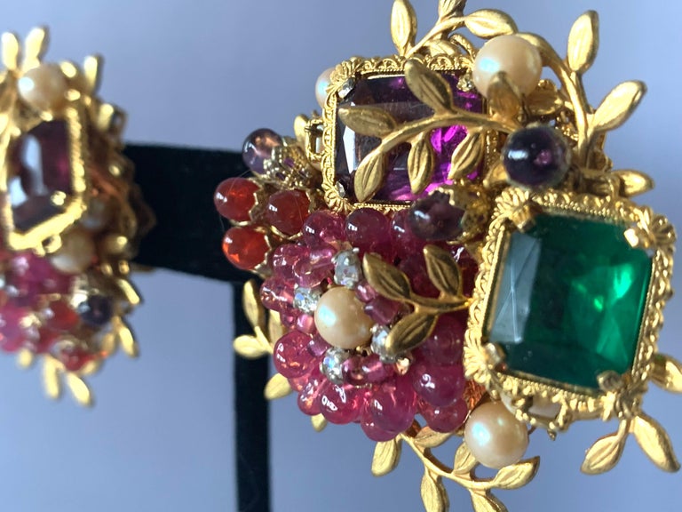 One-of-a-kind ornate clip-on earrings by William de Lillo and Robert F. Clark, gilt metal, intricately beaded in layers with fuchsia color glass beads and accented by large glass faux amethyst and emeralds.