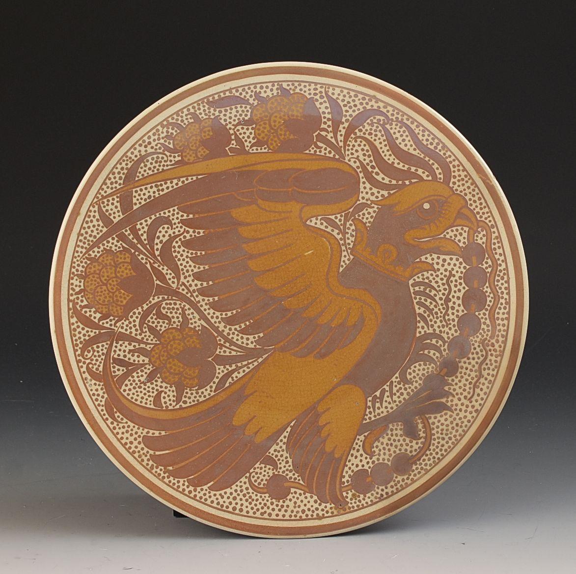 Assiette en forme de plat de 23 cm de diamètre superbement décorée, conçue par William De Morgan. Elle date des années 1880 et représente un aigle ou un animal similaire au milieu d'une décoration feuillue. Le bord a subi une restauration mineure et
