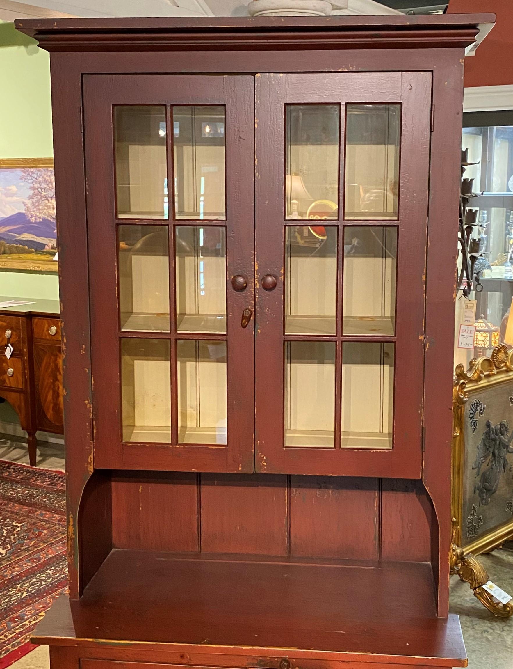A fine diminutive step back country pine cupboard in the 19th century style, with molded cornice surmounting two upper glass panel doors, which open to a white painted interior with three shelves, all with plate rails, over a lower case with two