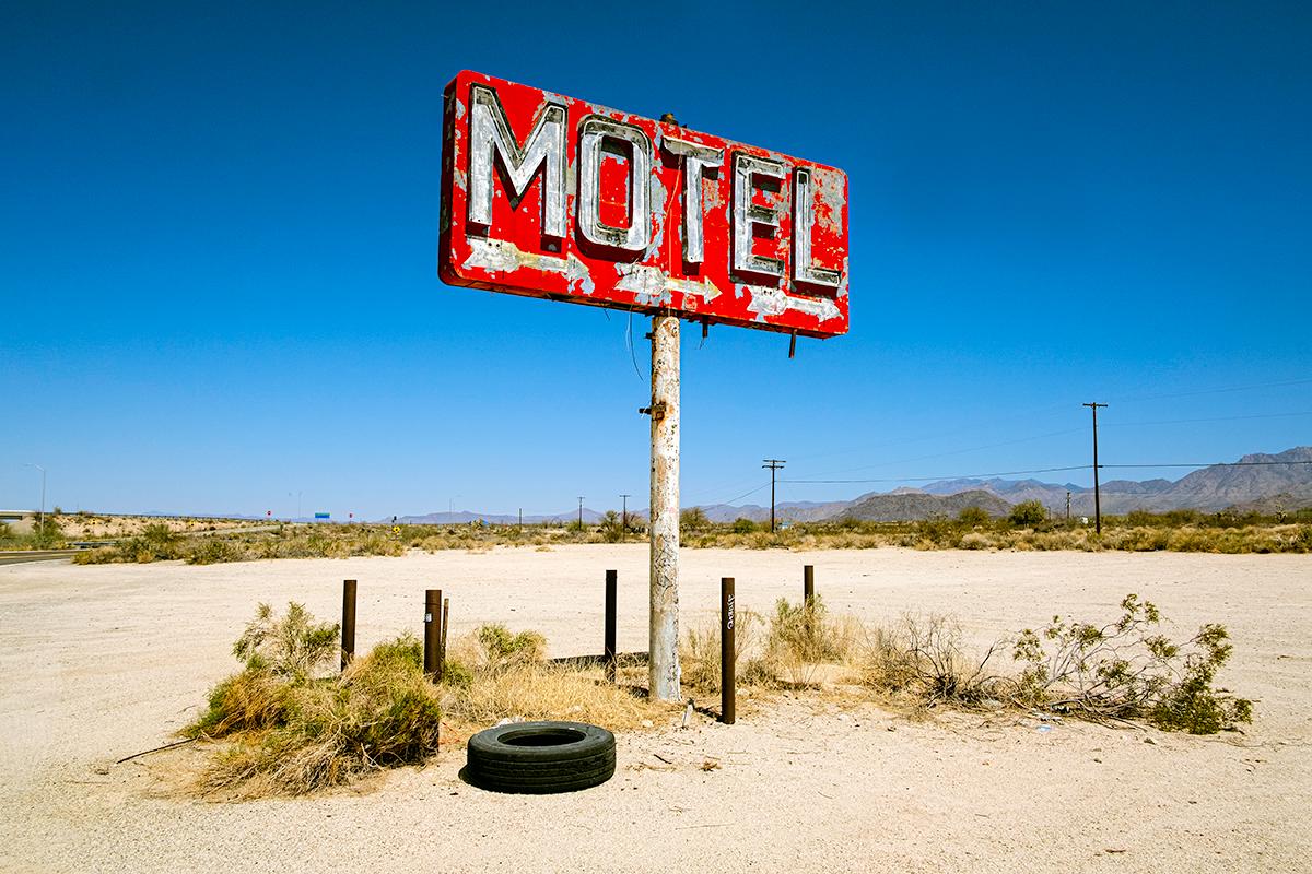Color Photograph de William Greiner - Motel, Needles, CA - Paisaje en color, Desierto, Oeste, Montañas, Señal, Neumático