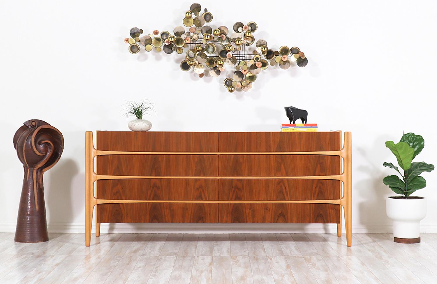 Sculptural Scandinavian Modern eight drawer dresser designed by William Hinn for Urban Furniture’s “Swedish Guild Collection” in Sweden, circa 1950s. This rare and sleek design features a sculpted biomorphic walnut wood body with beech wood carved