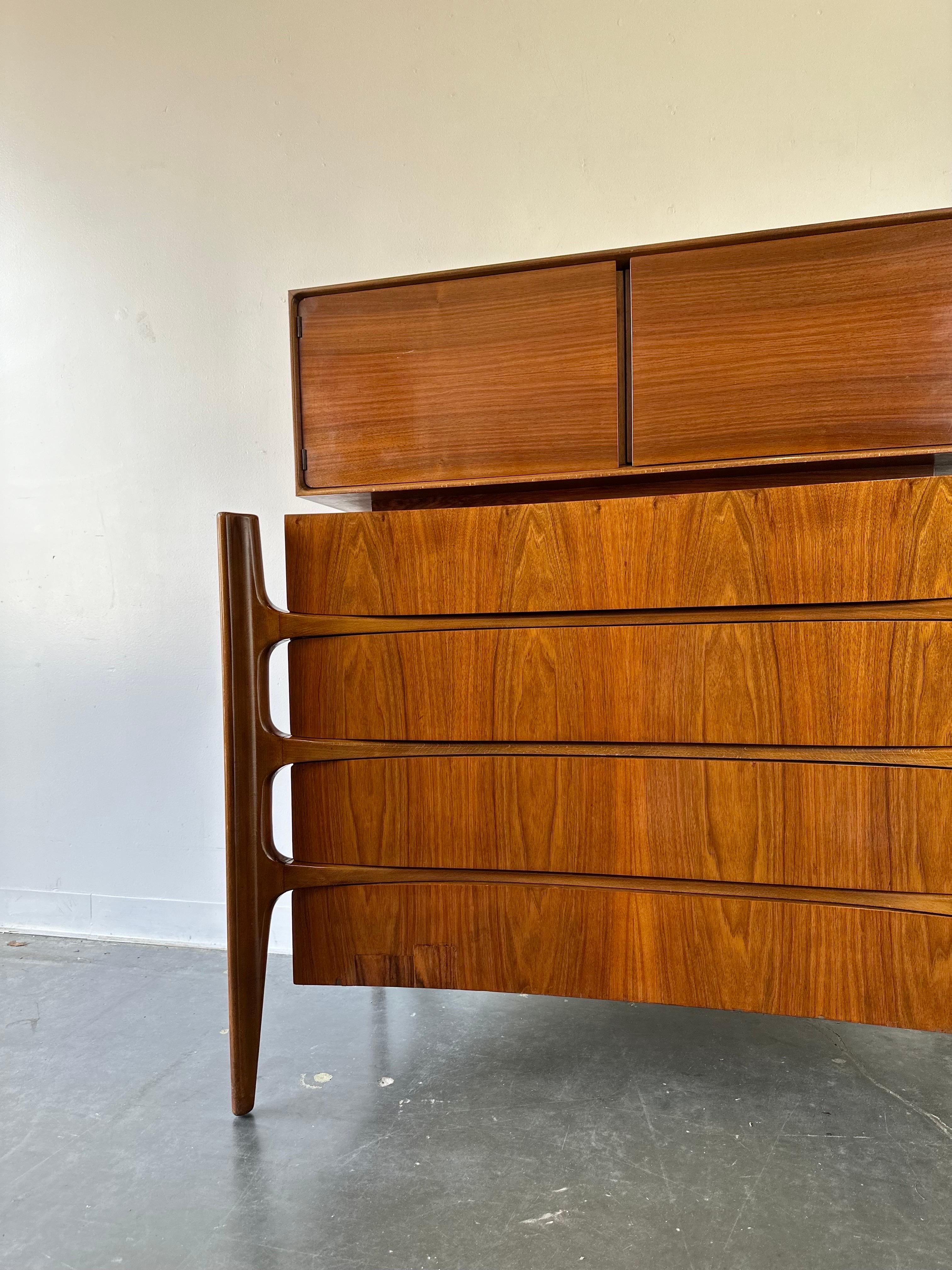 William Hinn Exoskeleton Highboy Dresser

This is in phenomenal condition with minor signs of wear ( one vintage veneer patch on bottom drawer )

Curved front , sitting on exoskeleton legs.

Dim:
