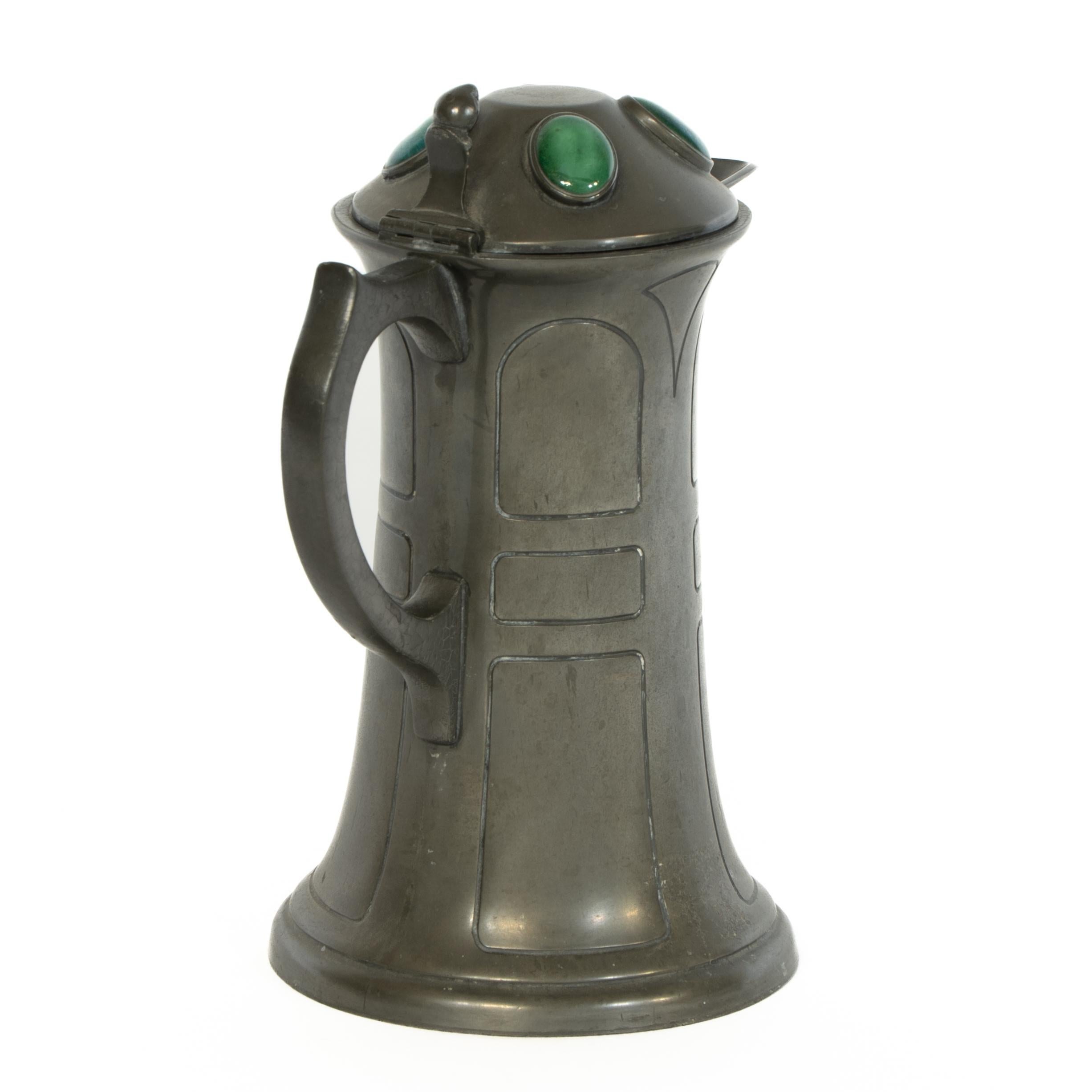 William Williams. Brocca in peltro di Art Decorative Crafts con quattro gioielli Ruskin a occhio di bue incastonati nel coperchio, con un fermo posteriore quando viene aperto, e decorazioni geometriche sul corpo principale con una base svasata. Si