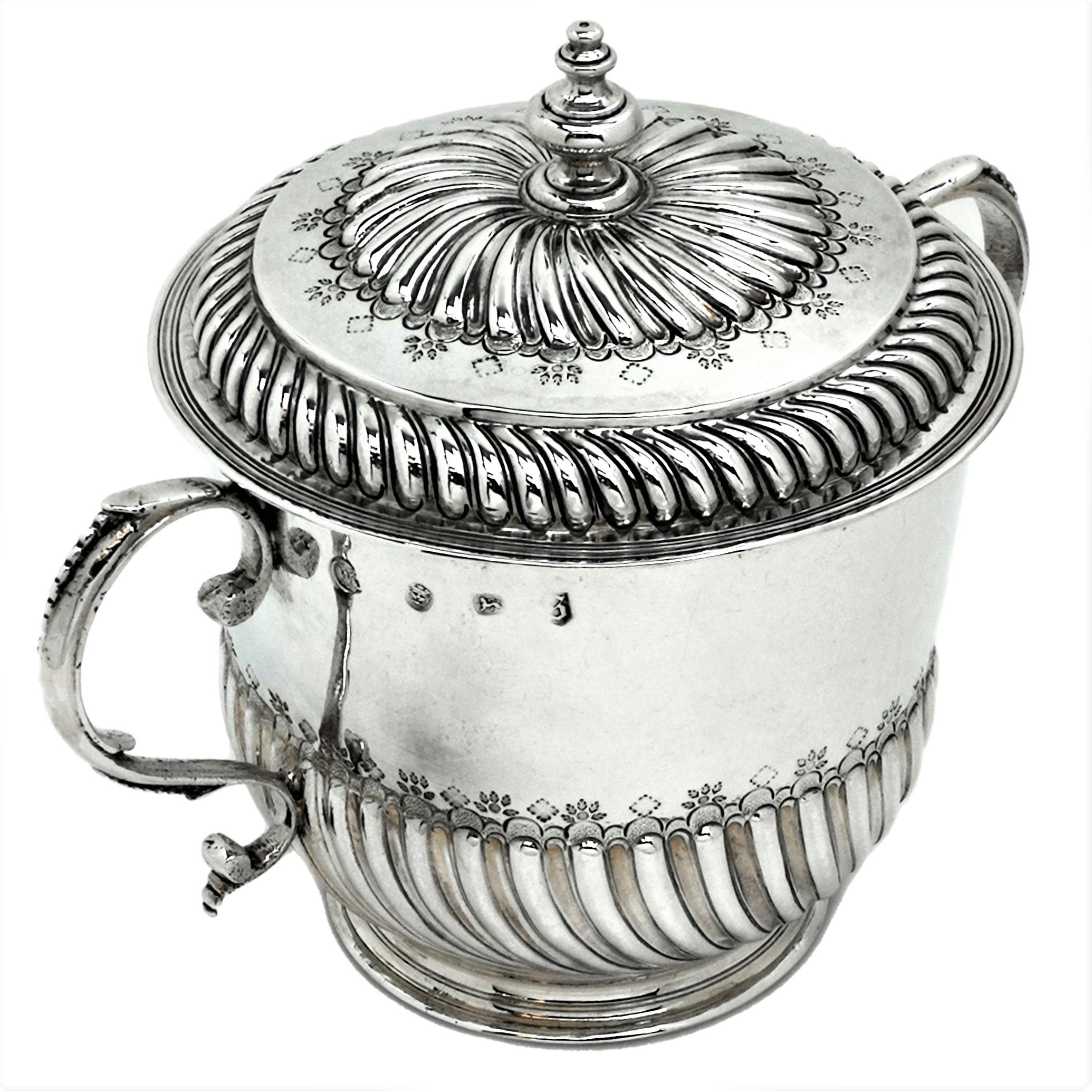 An early Antique William III solid Silver Porringer with fitted lid. This substantial Porringer has two scroll handles beaded embellishments. The body of the Porringer is decorated with a chased half fluted design and topped with an engraved