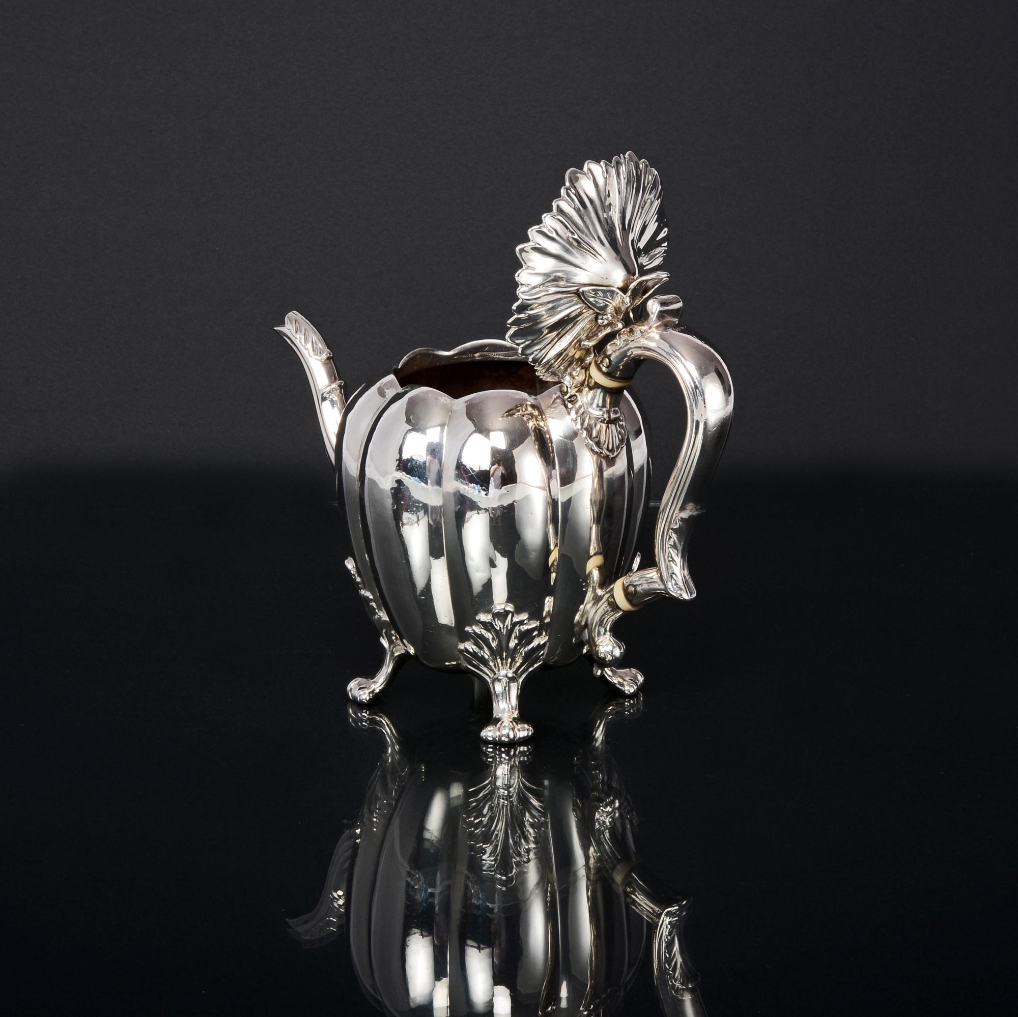 An unusual and decorative antique silver teapot in the form of a pumpkin or melon, with a moulded leaf lid and cast finial. This wonderful silver teapot is mounted on four cast leaf and scroll feet and has an insulated silver handle. It is a