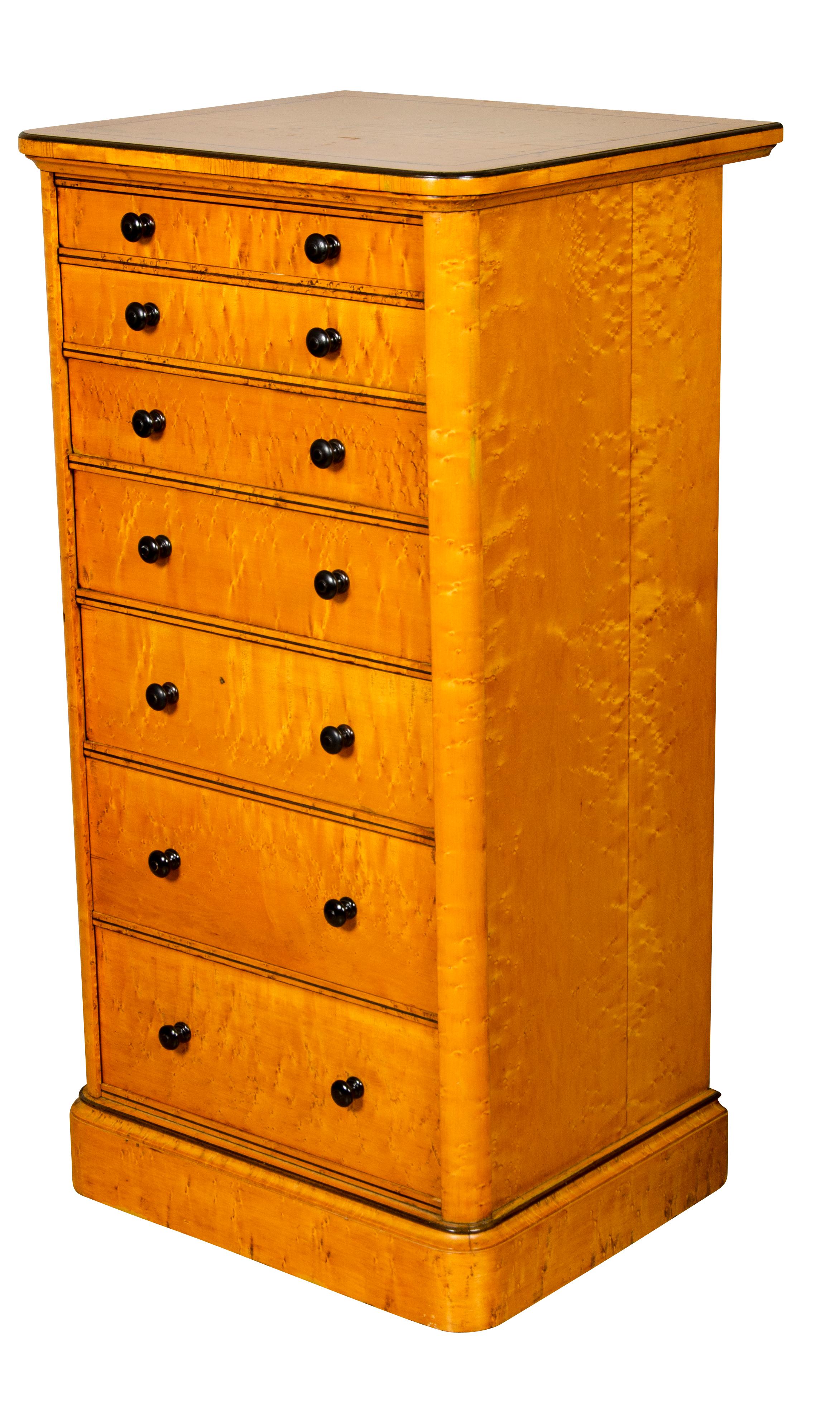 Con tablero cuadrangular con encordado de ébano sobre siete cajones graduados con pomos de madera y mecanismo de cierre basculante que cierra todos los cajones, elevado sobre una base de plinto. Holland & Sons era un importante fabricante de muebles