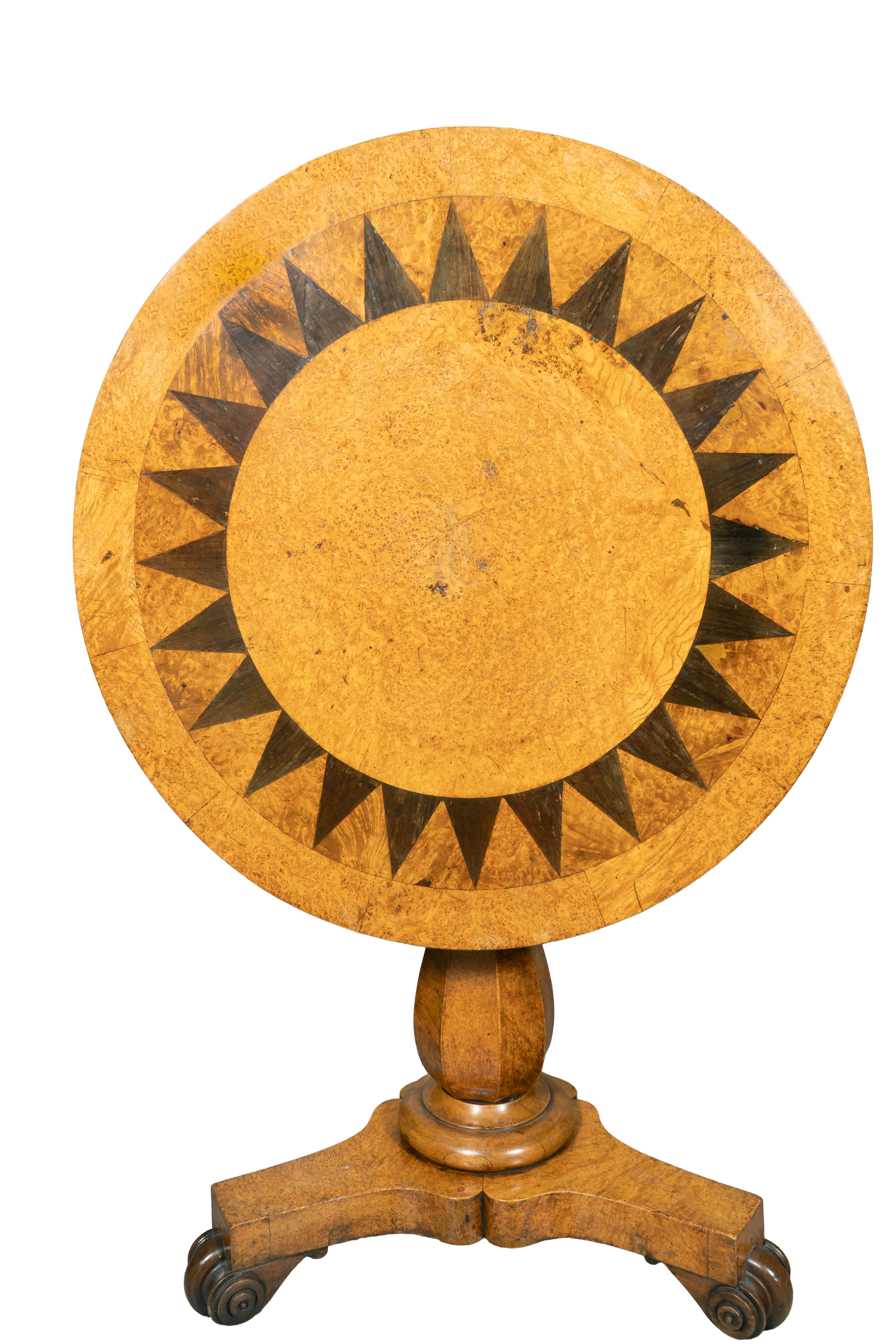 Plateau circulaire incliné avec incrustation de ronce et de dents de scie circulaires en ébène. Support octogonal tourné et base tripartite avec pieds en volutes sculptés.