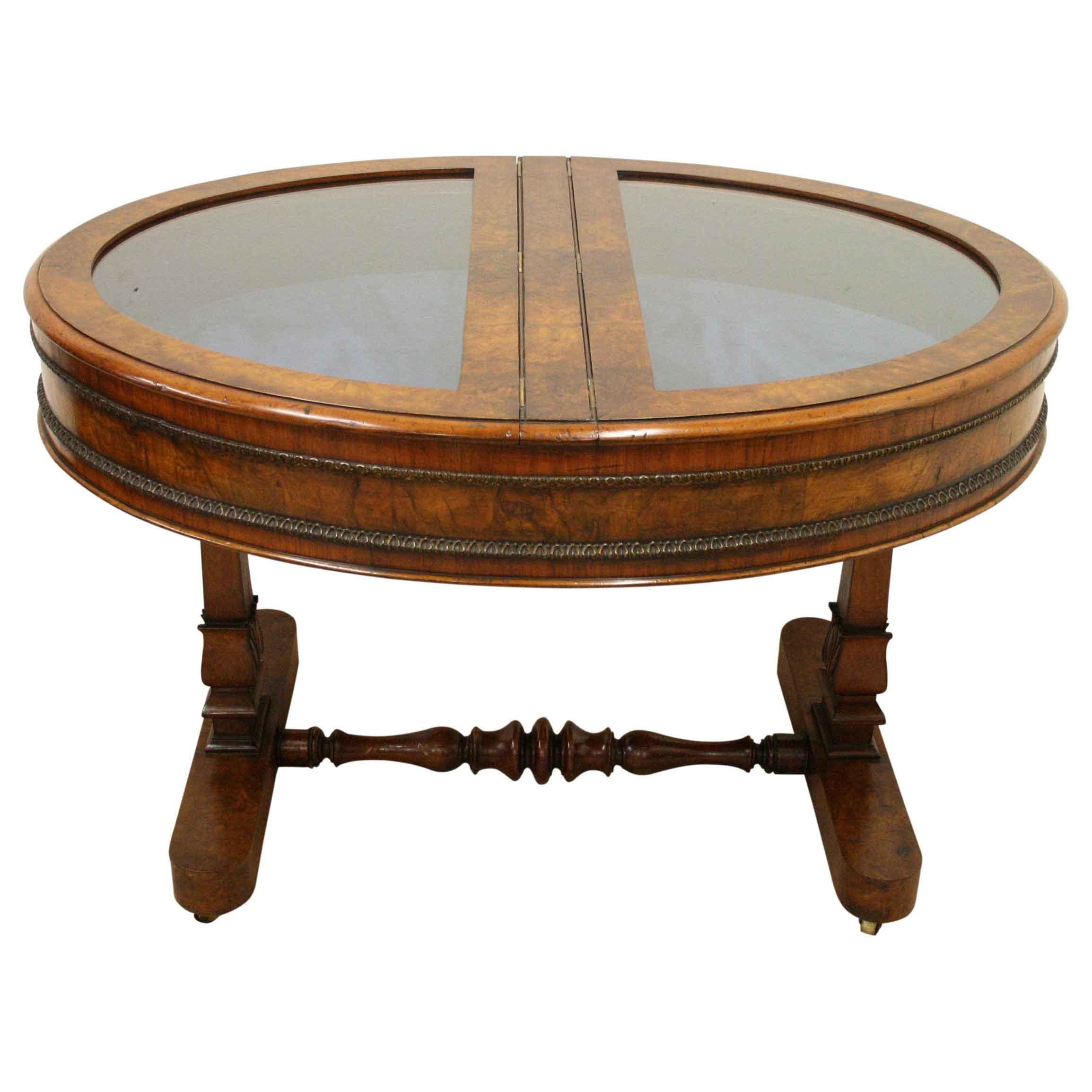 Late George IV/early William IV burr walnut display table/bijouterie table, circa 1830. The oval top is divided into two D shaped glazed doors, which open and are held in place with a brass locking arm. The inside is lined in felt and the frames are