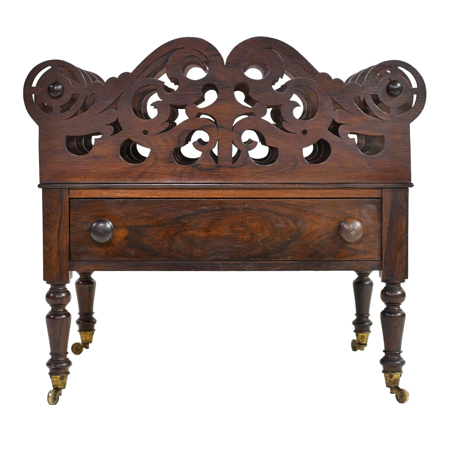An exquisite English sheet music rack or Canterbury in prized rosewood with four fretwork partitions, one drawer, and resting on turned legs mounted on brass casters. England, circa 1830. Offers original turned and threaded pulls which are also made