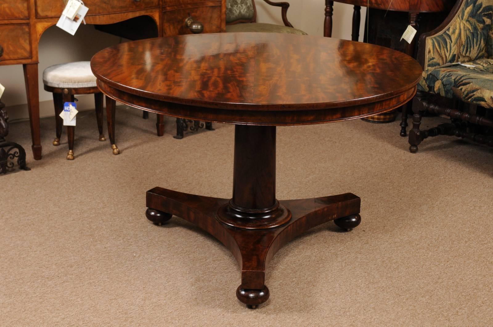 The William IV English mahogany centre table with highly figured grain circular top resting on pedestal base and bun feet. The table with tilting mechanism.

 