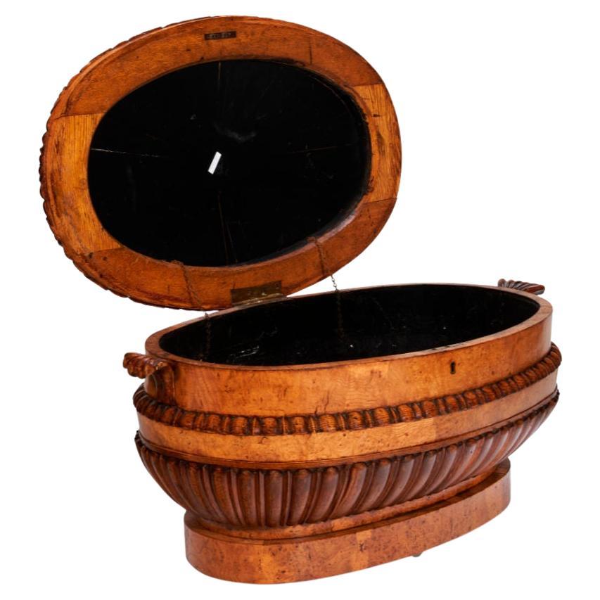 Our English wine cooler dating from the William IV (1830-1837) period is crafted from oak, pollard oak and burr elm and features a hinged top with gadrooned finial, borders with lotus leaf and beaded designs and vessel with prominent gadrooning and