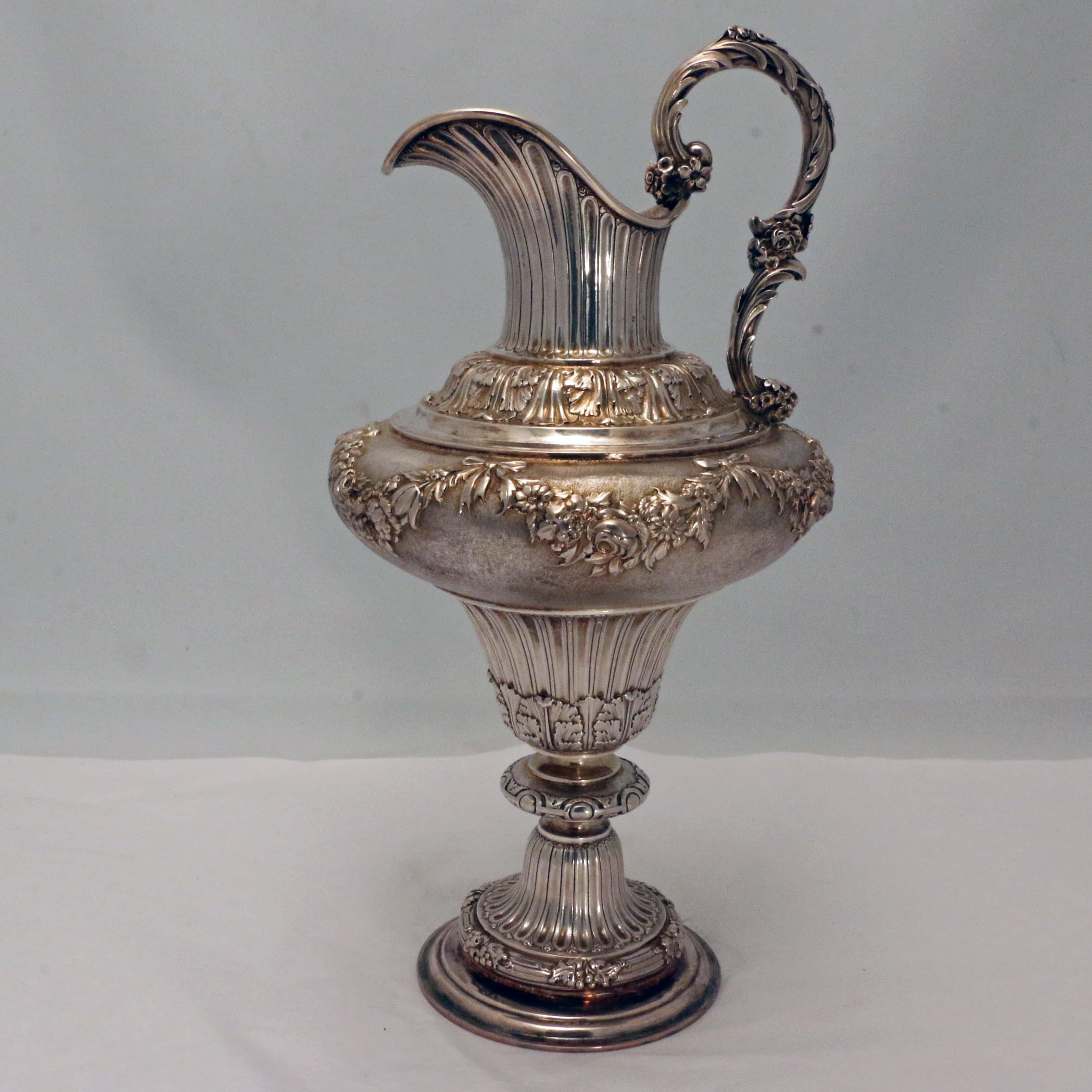 Made in London in 1832, this jug is both useful and ornemental. Raised on an elegant foot and fluted stem, the baluster body swells to a pounced ground repoussee with floral garlands, in turn surmounted by an acanthus band, a motif reiterated by the