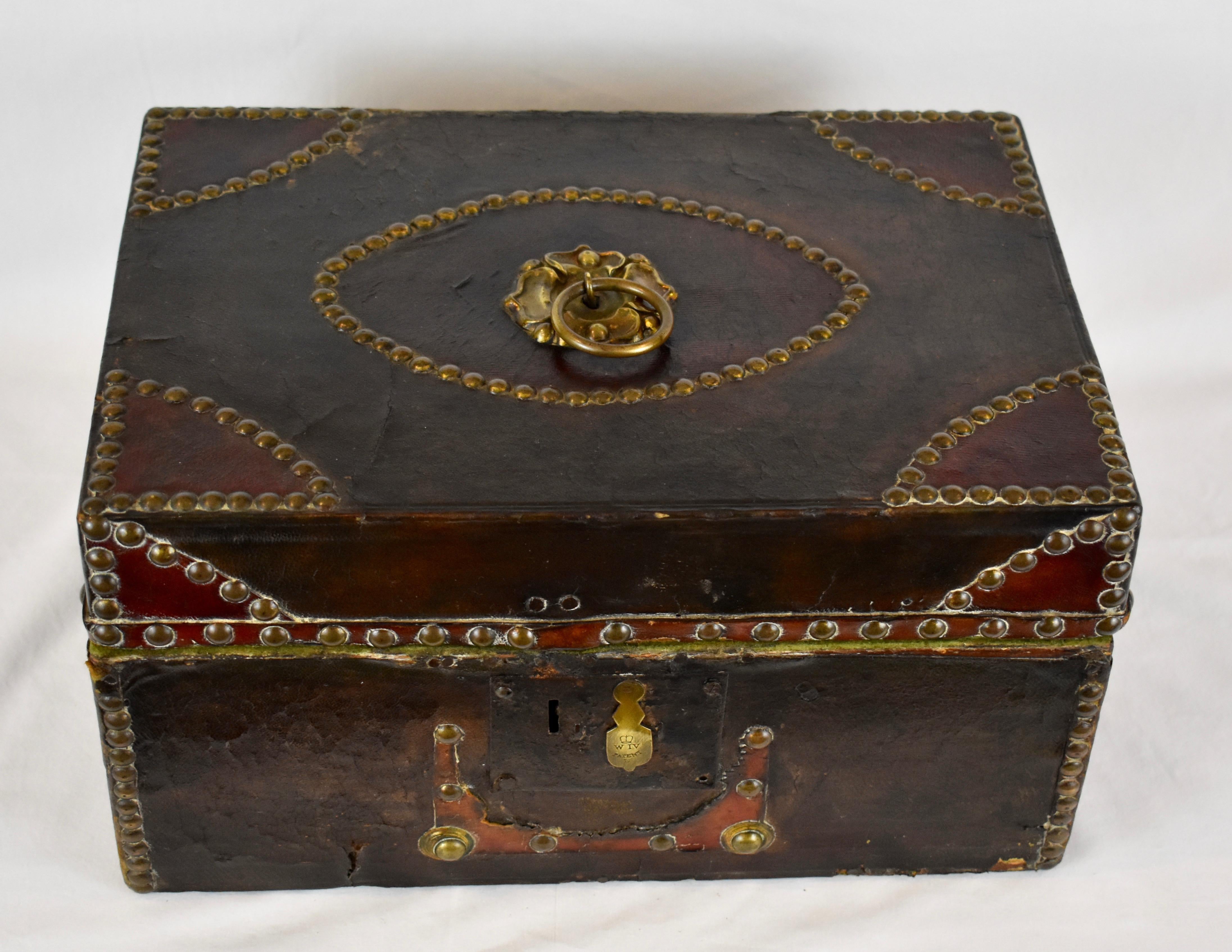 This is a handsome William IV pine document box, clad in dark brown and burgundy leather, and studded in brass. There is a brass ring pull with a pressed brass floral backplate in the center of the lid. The iron lock has a brass keyhole cover
