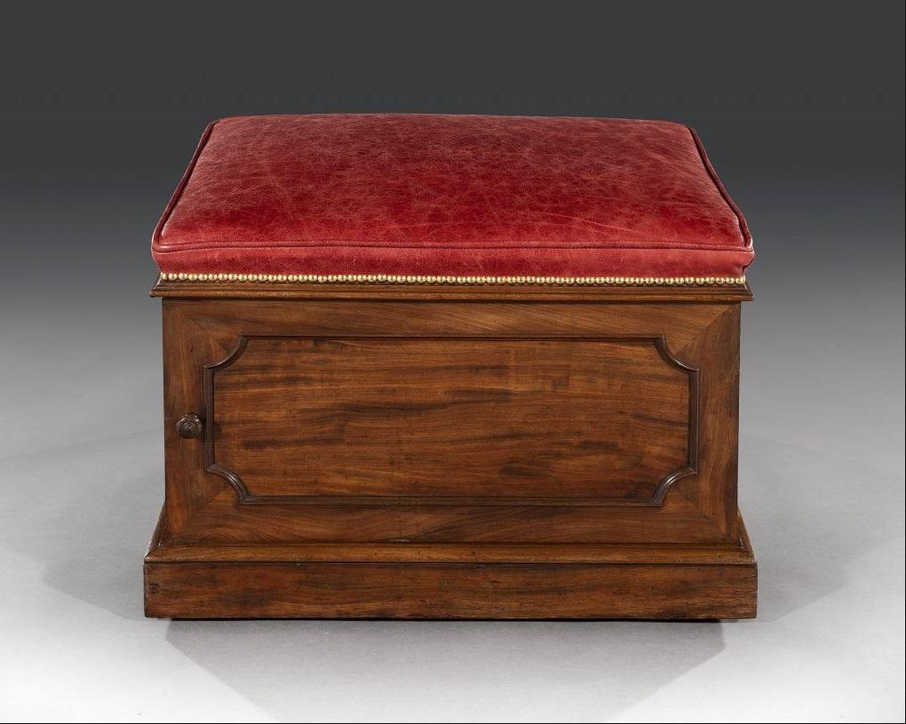 William IV mahogany and leather box stool is of unusual form and made by Doveston Bird and Hull. The rectangular padded seat is newly upholstered in good quality red hide with a piped edge and close brass studs and sits above a shaped mahogany