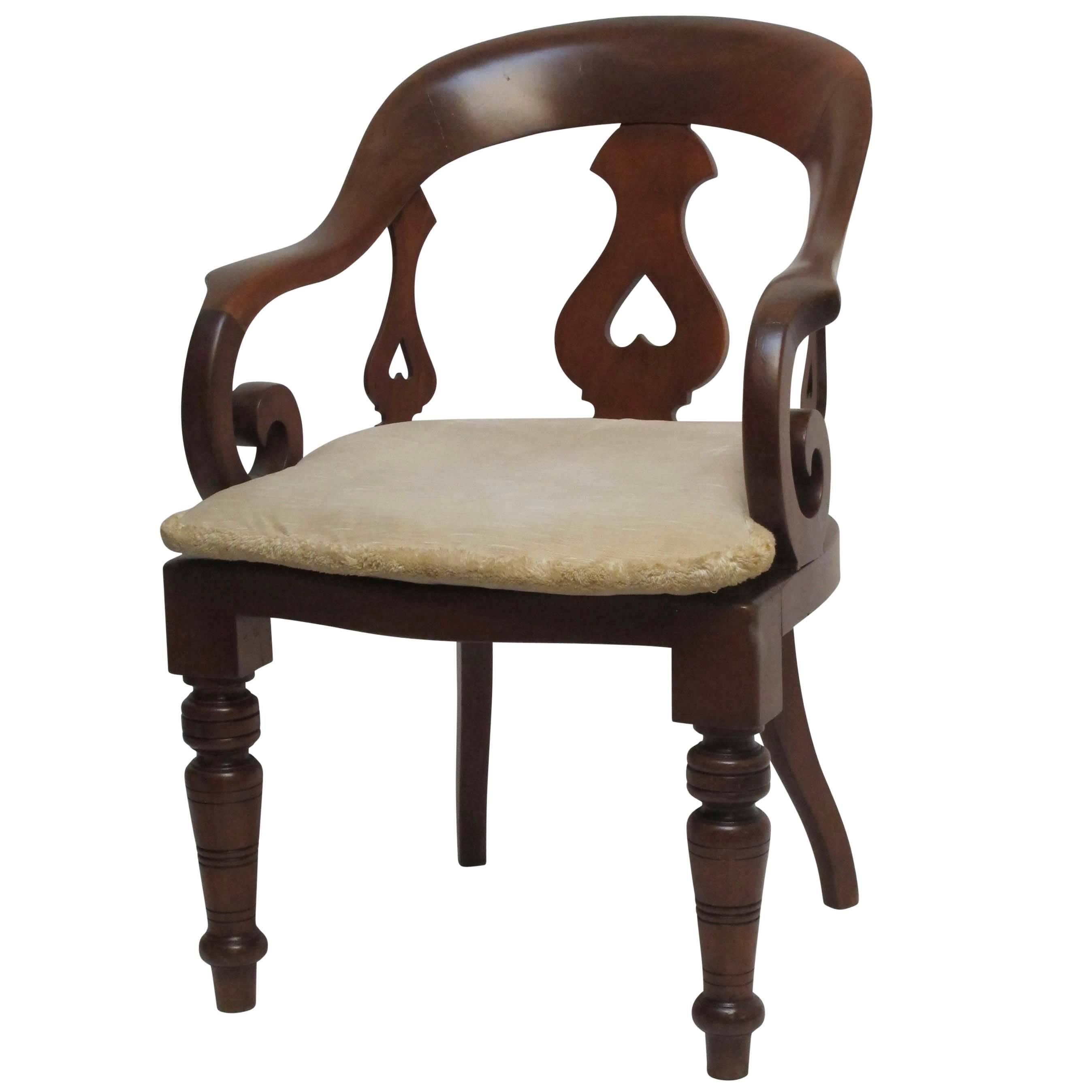 Mahogany barber's or dentist's chair with single back splat and two smaller side splats with heart shape cut-outs and hand woven cane seat. The sturdy scrolling arms curving around, having turned front legs and saber rear legs, England, circa