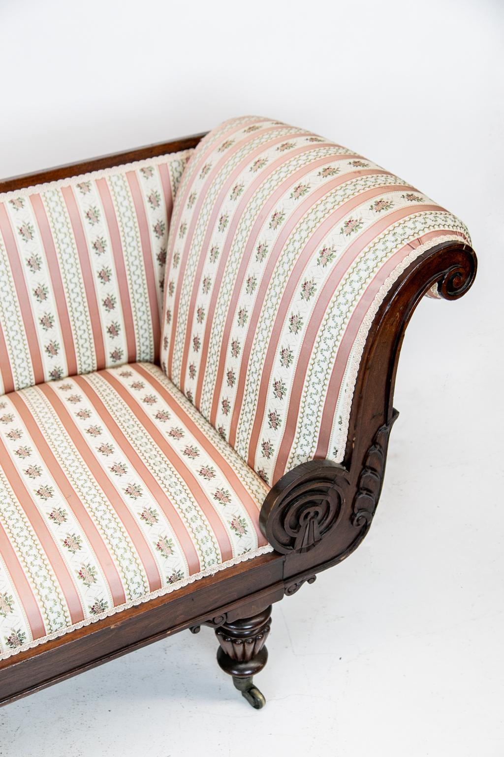 William IV mahogany chaise lounge, with reeded legs on the original brass castors, scrolled support brackets. It has stylized acanthus leaf and tassel carved on the back frame. There is arabesque scroll work on the back foot. It has newly