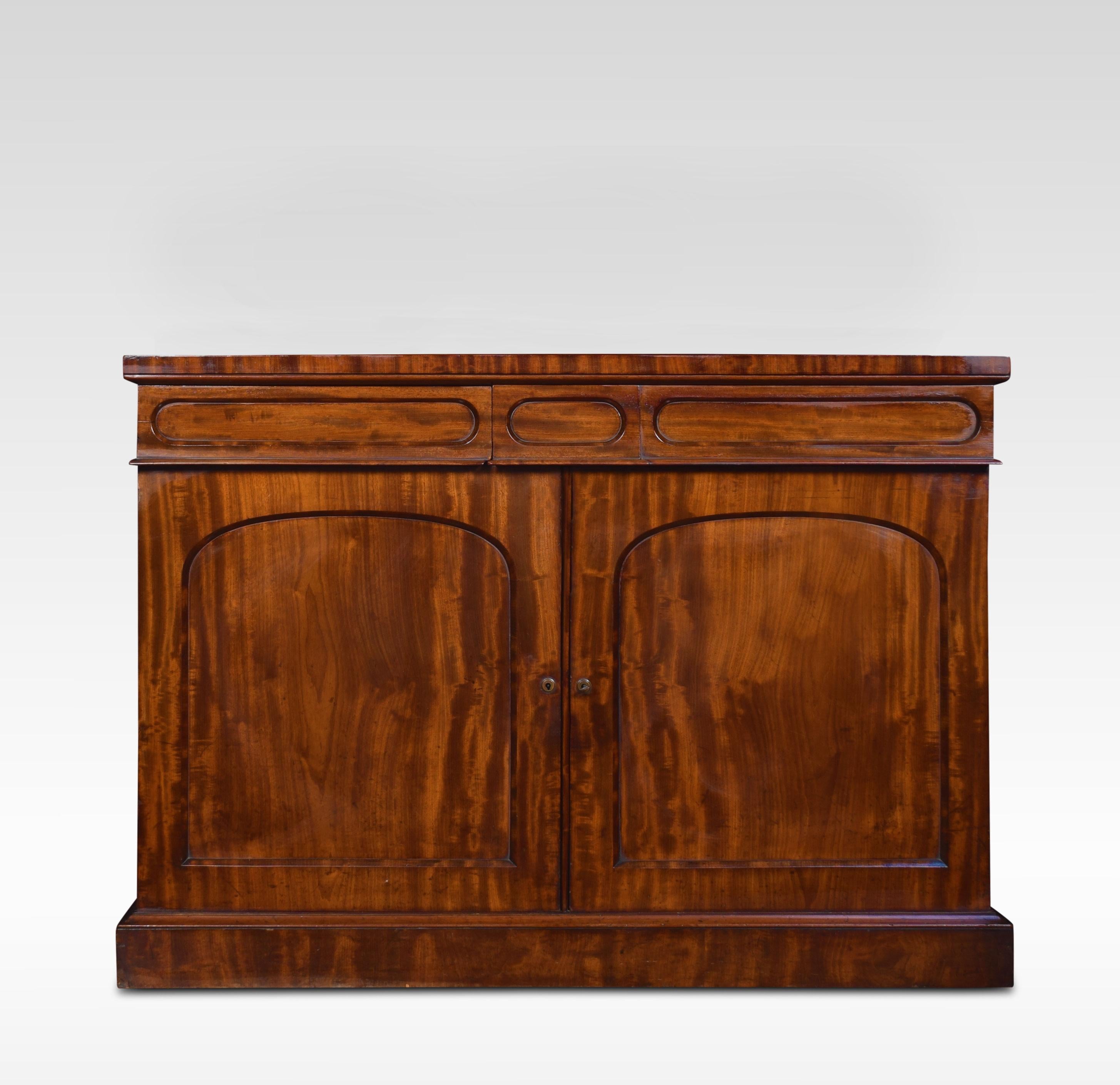 William IV mahogany chiffonier, the raised gallery back with carved foliated decoration above the central oval mirror. The large rectangular well figured top above a moulded frieze fitted with two drawers and a pair of panel doors below opening to