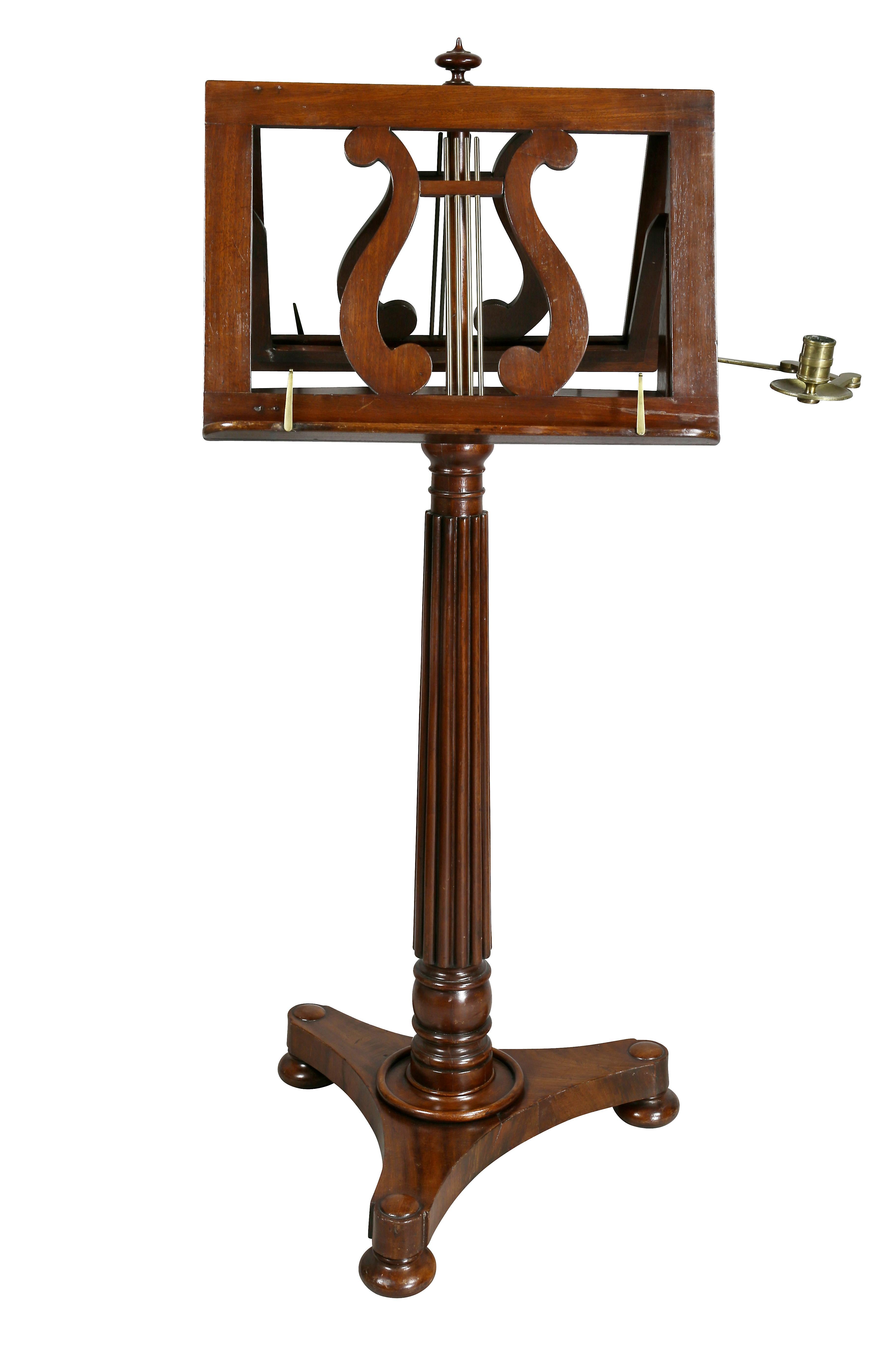 With central finial and double lyre ratcheted sheet music holders and a single attached brass candle arm, raised on a turned reeded support, shaped triangular base and bun feet.