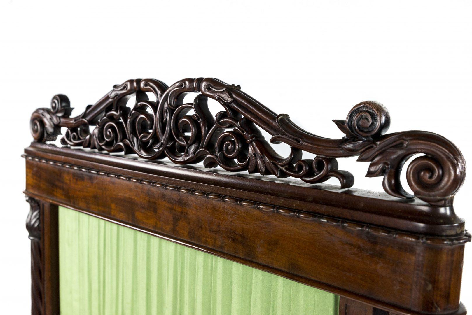 A William IV mahogany atributed to Gillows, profusely carved with scrolling leaves and lappets, with a pleated silk panel flanked by spiral twist batons, above a conforming base and on brass castors, 

Gillows of Lancaster and London, also known