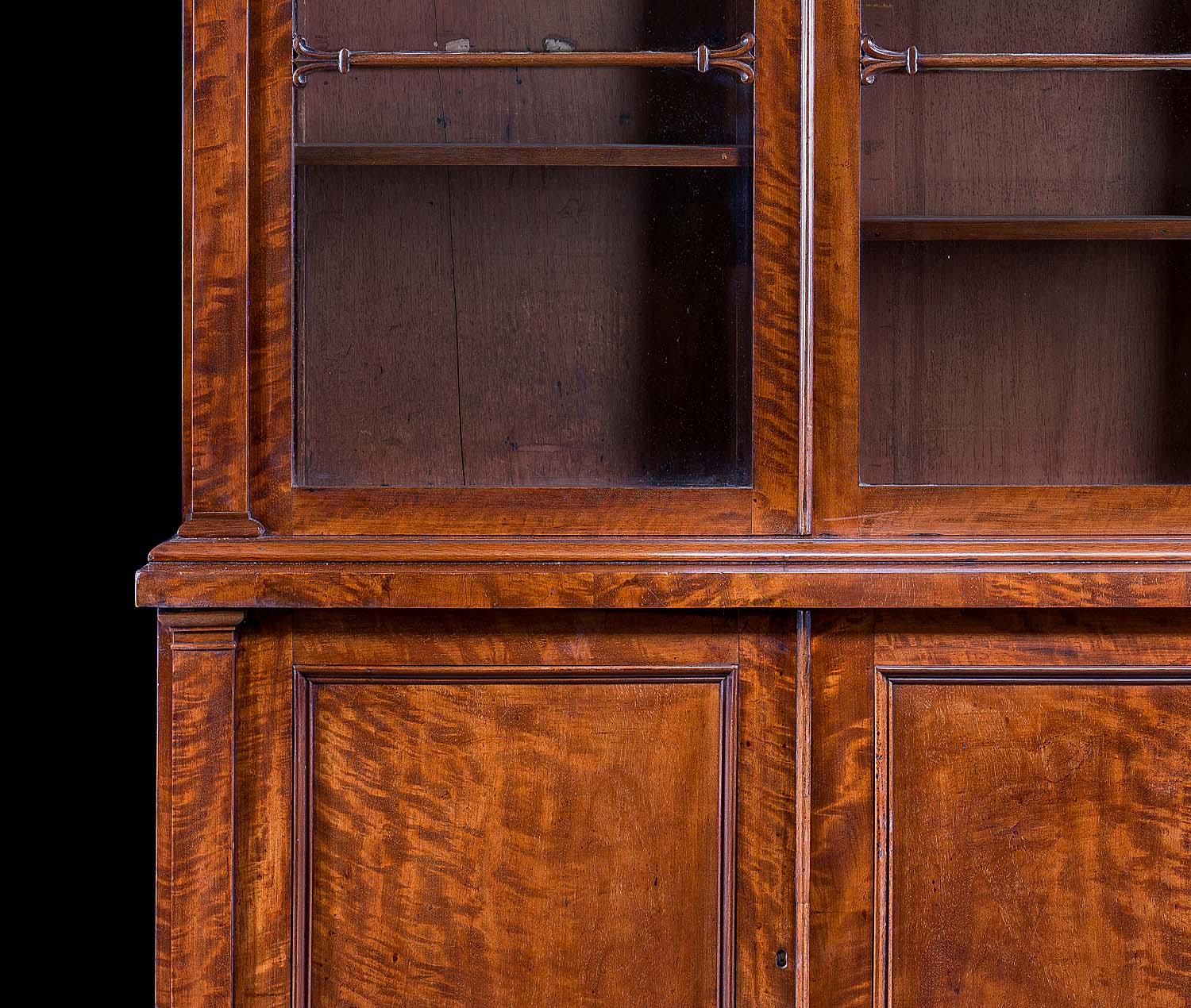 A fine William IV mahogany library bookcase with a moulded cornice above three glazed doors. The left and right doors are hinged, the central door slides. The cabinet base also features a central sliding door flanked by a pair of hinged doors and is