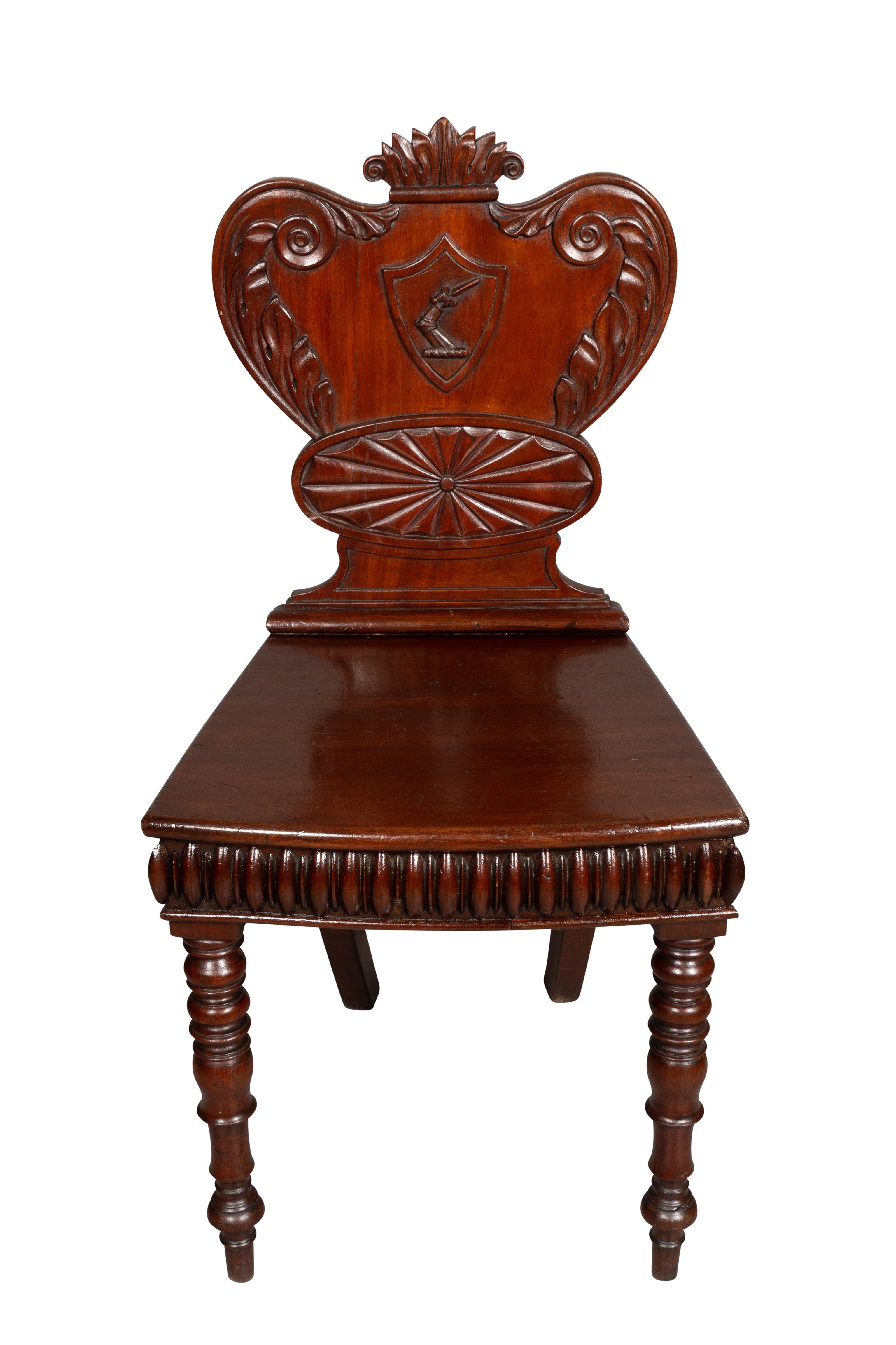 An interesting chair with carved back and central coat of arms over an oval paterae. Slightly bowed seat with reeded seat rail raised on turned legs.