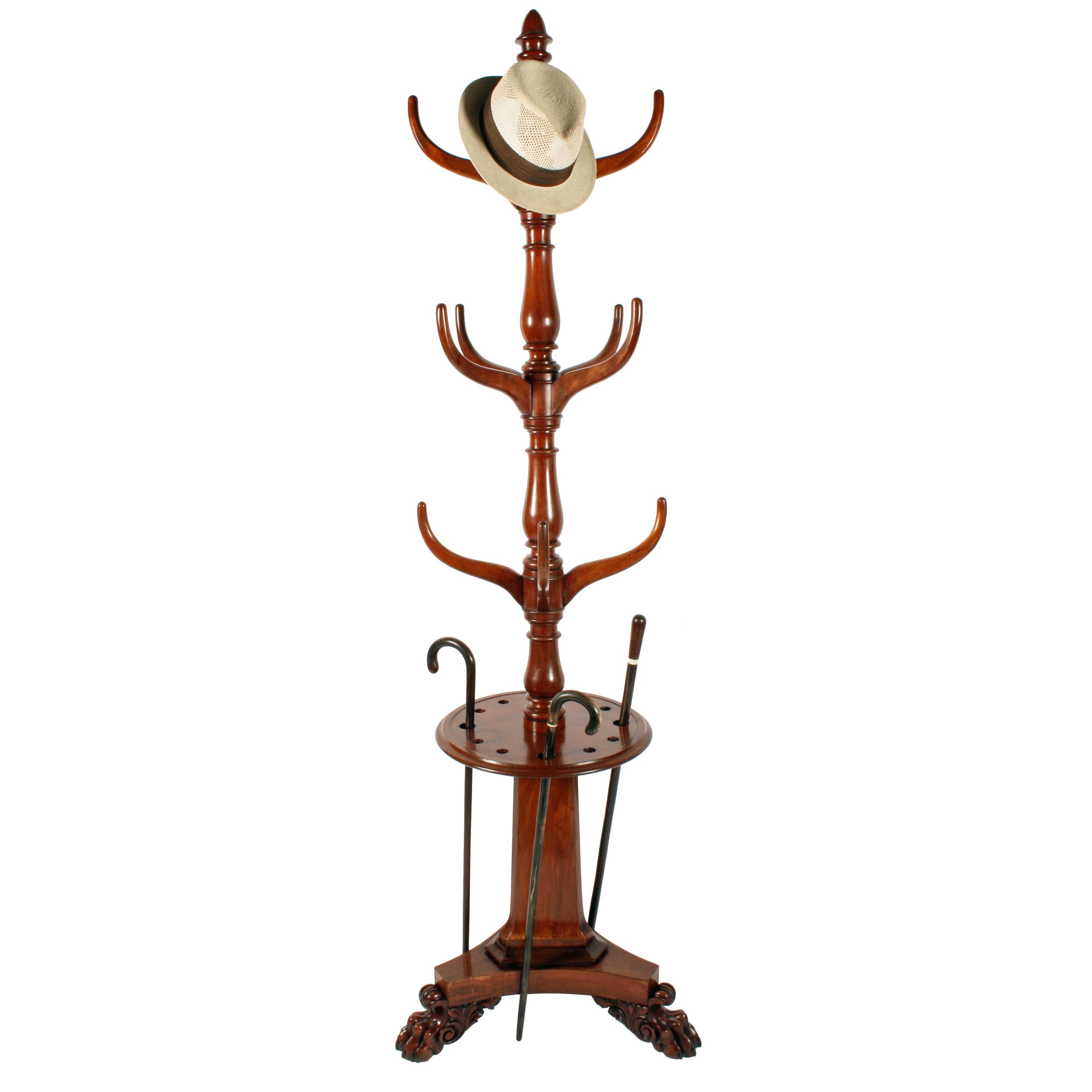 A magnificent 19th century William IV mahogany hall stand.

The stand has a turned centre column with twelve shaped hooks for hats and coats and is topped with a finial.

The stand has a triangular concave sided platform base that is raised on