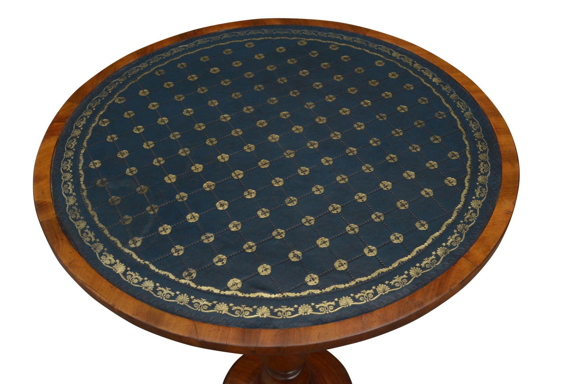 P071, fine quality mahogany lamp or occasional table, having tooled leather circular top raised on slander turned and carved column terminating in circular moulded base and three shaped feet. This antique table retains its original finish, color and