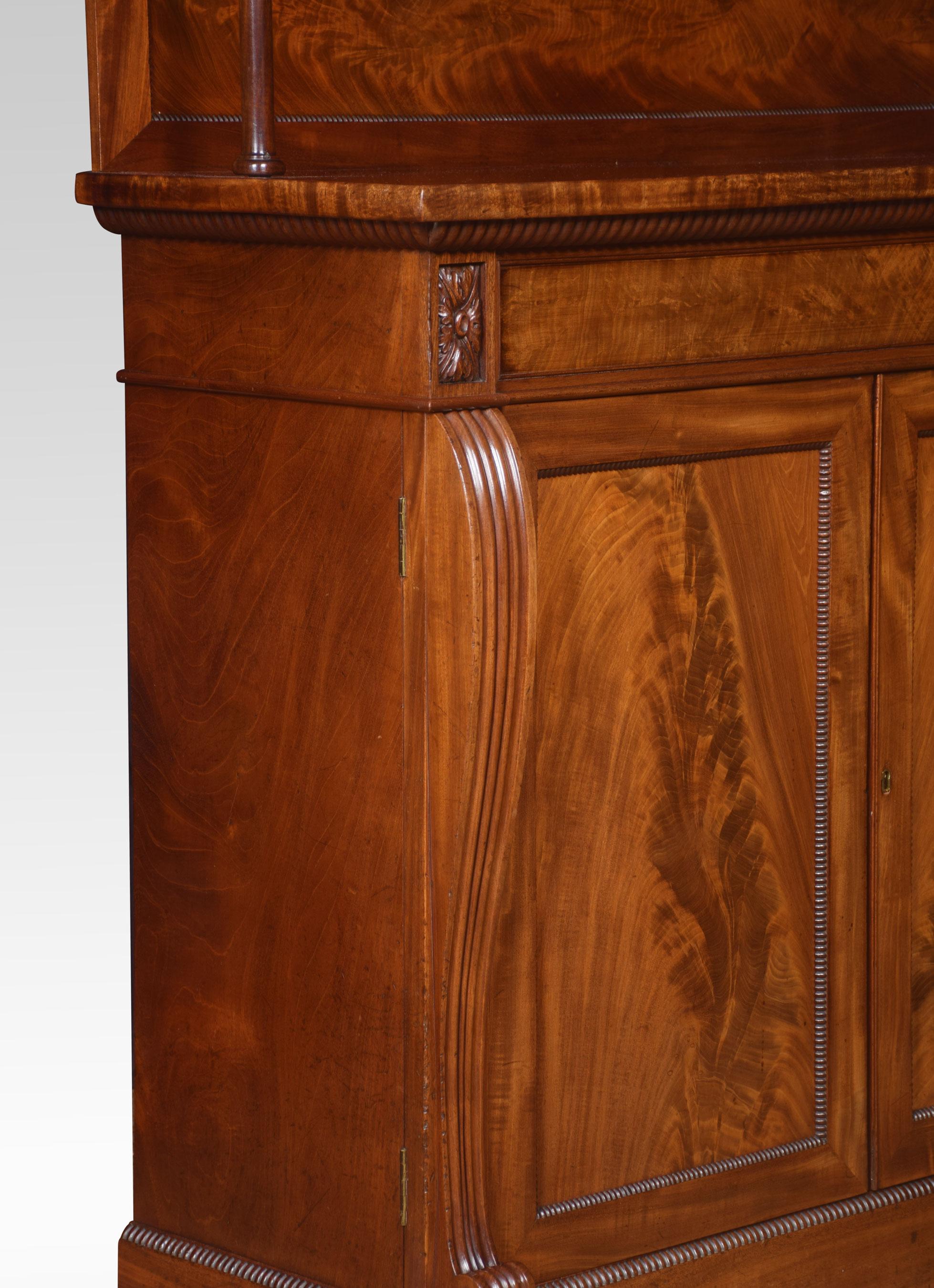 William IV mahogany two-door chiffonier, the raised gallery back with circular supports to the large rectangular top above flame mahogany-panelled freeze. The base section fitted with a pair of panelled doors flanked by shaped reeded columns. The