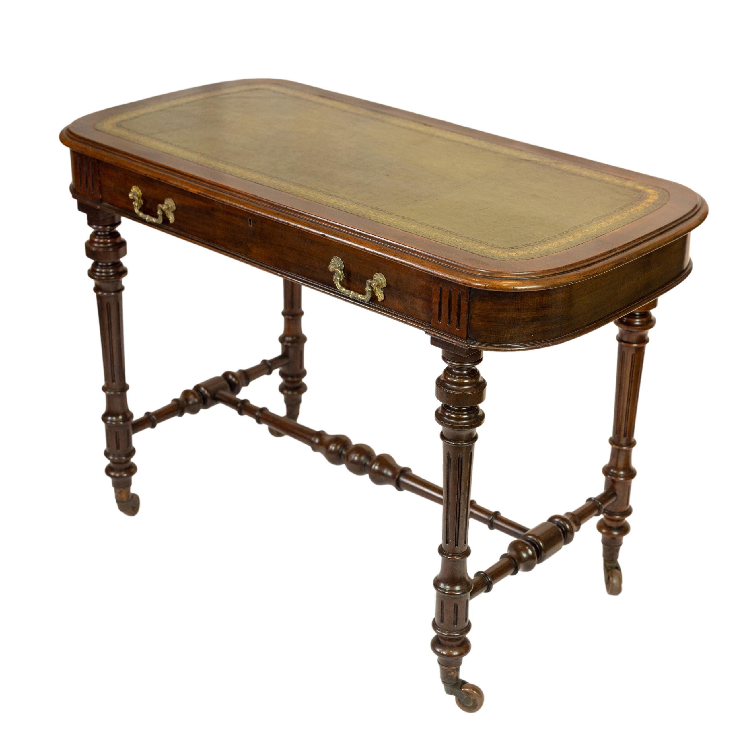 William IV Mahogany writing desk, of curved rectangular form, the writing surface with tooled and gilded green leather, above a single frieze drawer with original gilded bronze pulls, on turned, reeded legs and conforming stretcher, on brass