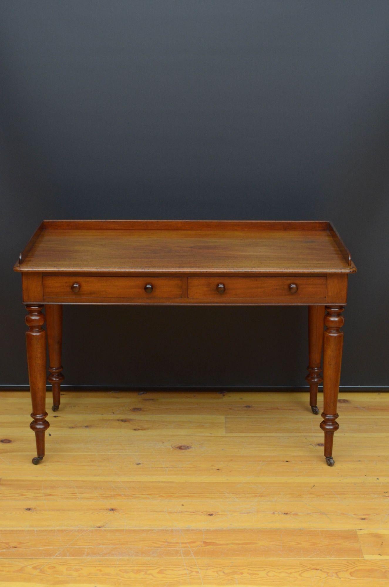 St038 William IV mahogany writing table or dressing table, having shaped upstand and figured mahogany top with moulded edge above two frieze drawers fitted with turned handles, all standing on turned, tapered leg terminating in brass castors. This