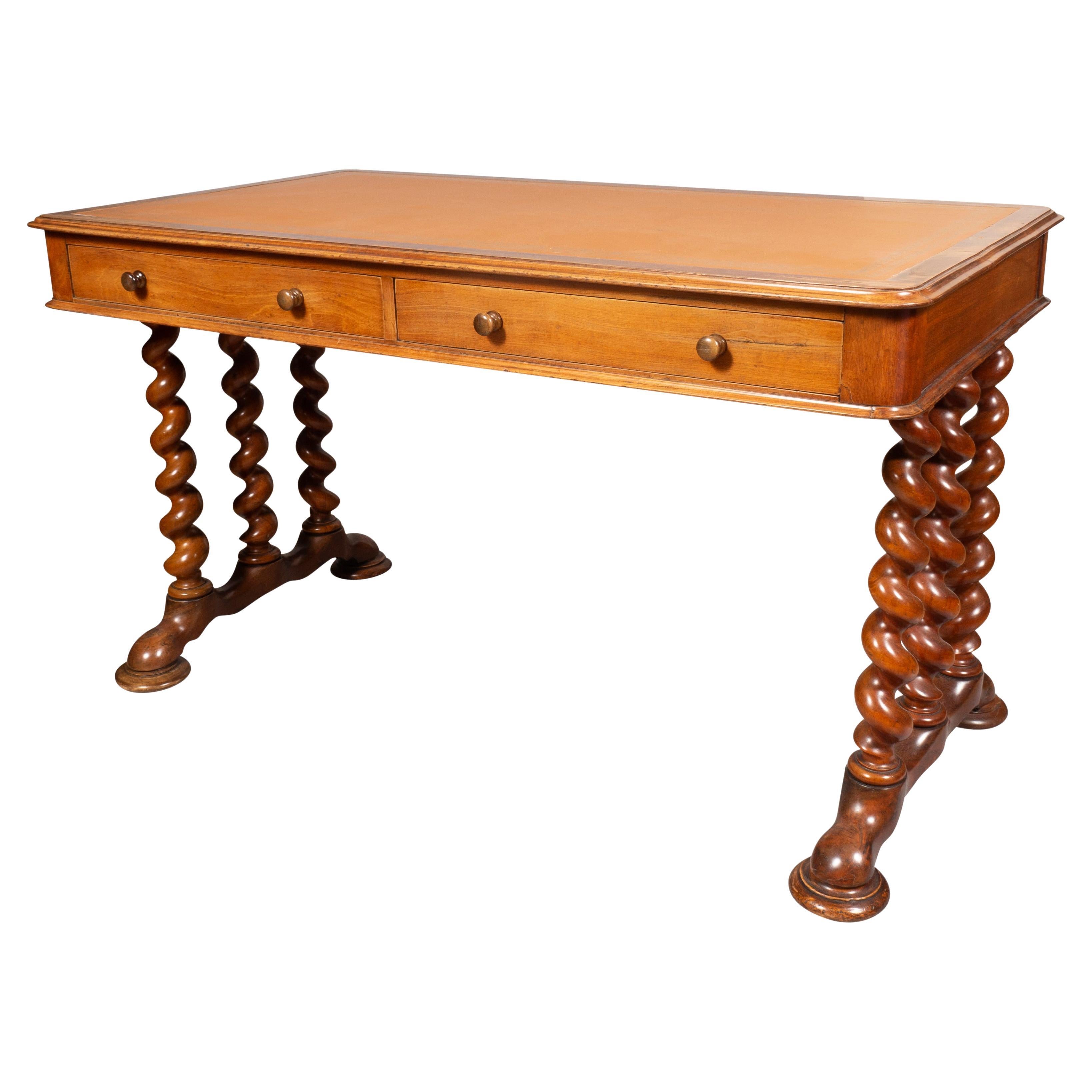 Rectangular top with inset brown leather over two drawers and two opposing false drawers each with wood knobs, raised on a barley twist trestle base. Disc feet with casters.