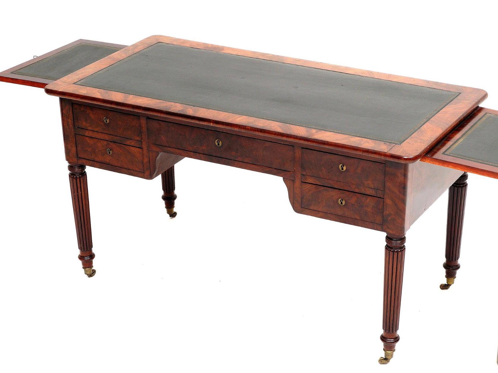 A William IV mahogany writing table / desk. Inset green tooled leather embossed writing surface, center drawer flanked by two short drawers. Inset tooled leather slides on either end, fluted and tapered legs ending in brass caps and castors.
Ex
