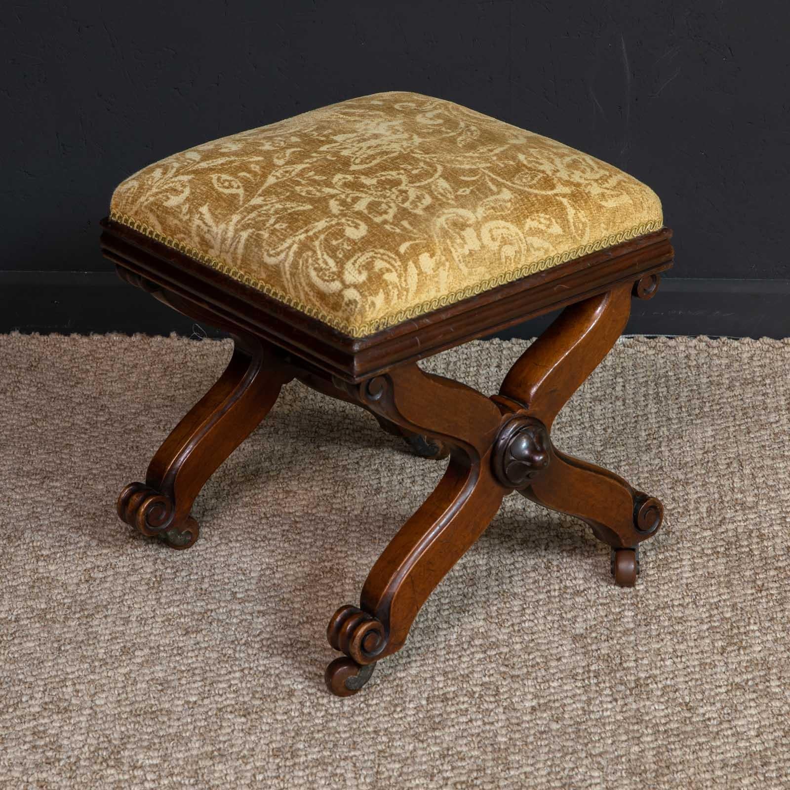 A William IV mahogany X framed stool of small proportions. One or two interesting features like the scroll feet and central carved bosses make it a cut above average. Very solid and sturdy with the gold patterned draylon being in very good