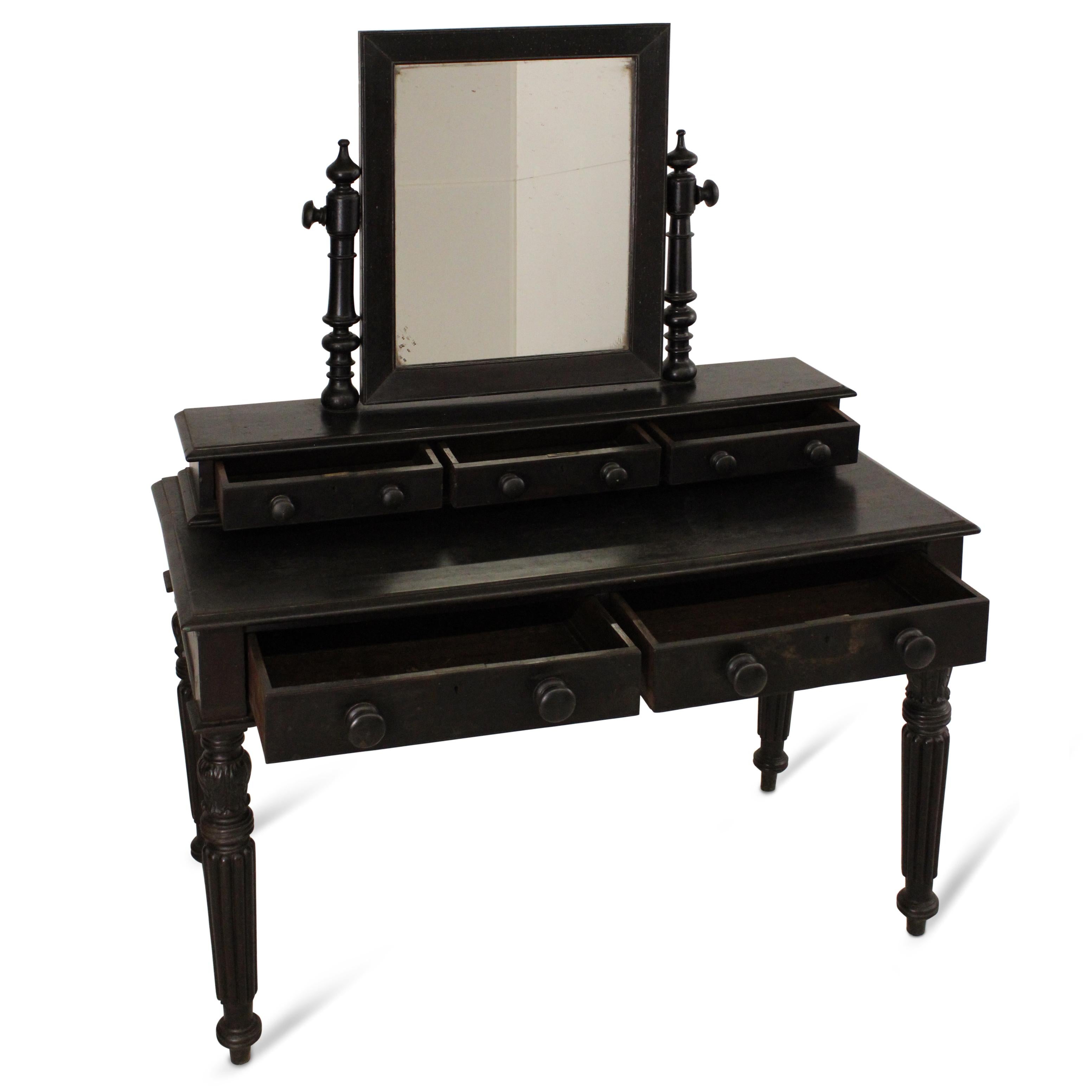 A William IV mahogany dressing table from a palace collection, distinguished by elegantly fluted feet and detailed carvings.This finely crafted dresser includes a set of drawers featuring original wooden knob pulls and a central mirror frame.