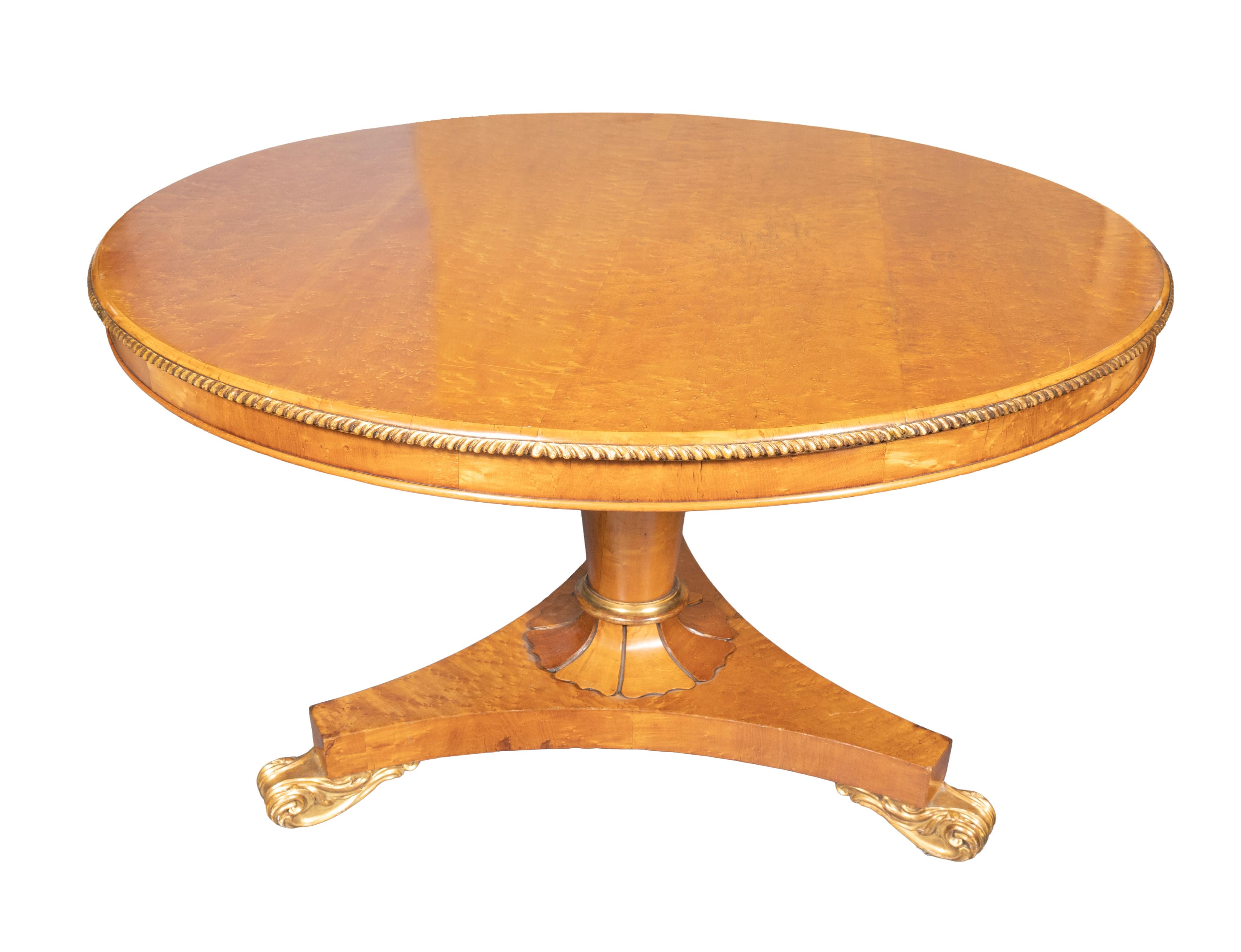 Circular hinged top with subtle gilded gadrooned edge on a circular tapered support and tripartite base with giltwood scrolled feet.