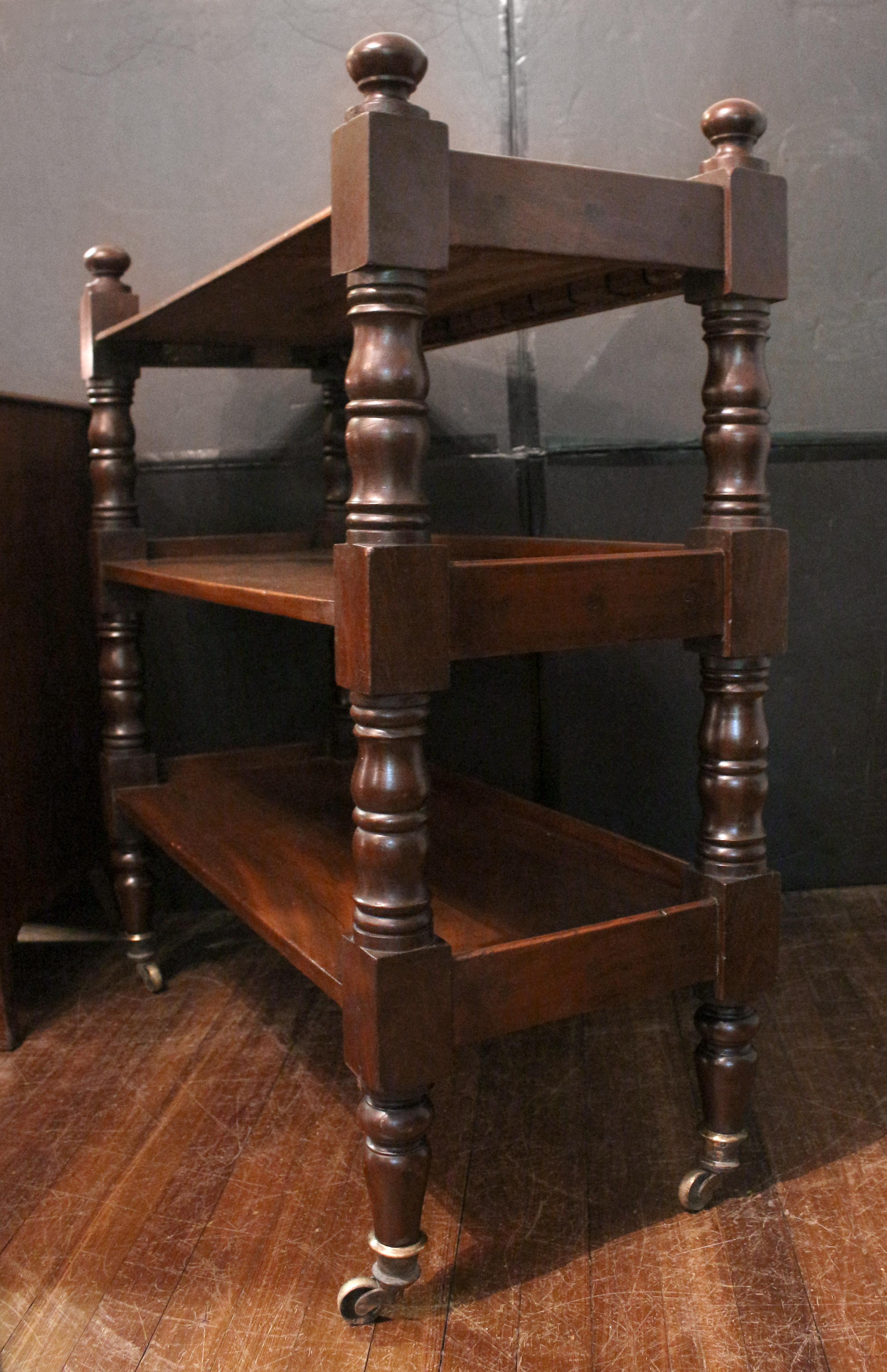 William IV Period English mahogany butler's trolley etagere or dumbwaiter. Circa 1830s-40s. Robust ring turned uprights with mushroom caps & ending in high quality brass caps & casters. Three tiers, edge with gallery; upper tier with molded front
