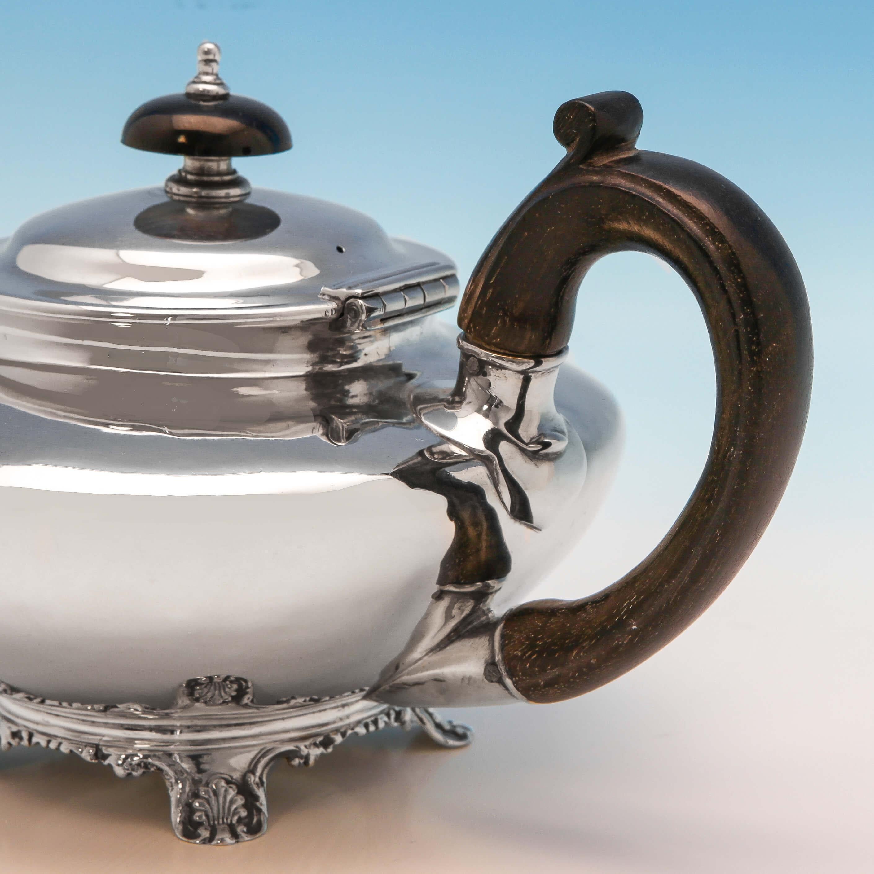 Hallmarked in London in 1835 by George Burrows II & Richard Pearce, this handsome, William IV, Antique Sterling Silver Teapot, is round in shape, plain in style, and features shell and scroll feet, and a wooden handle and finial. The teapot measures
