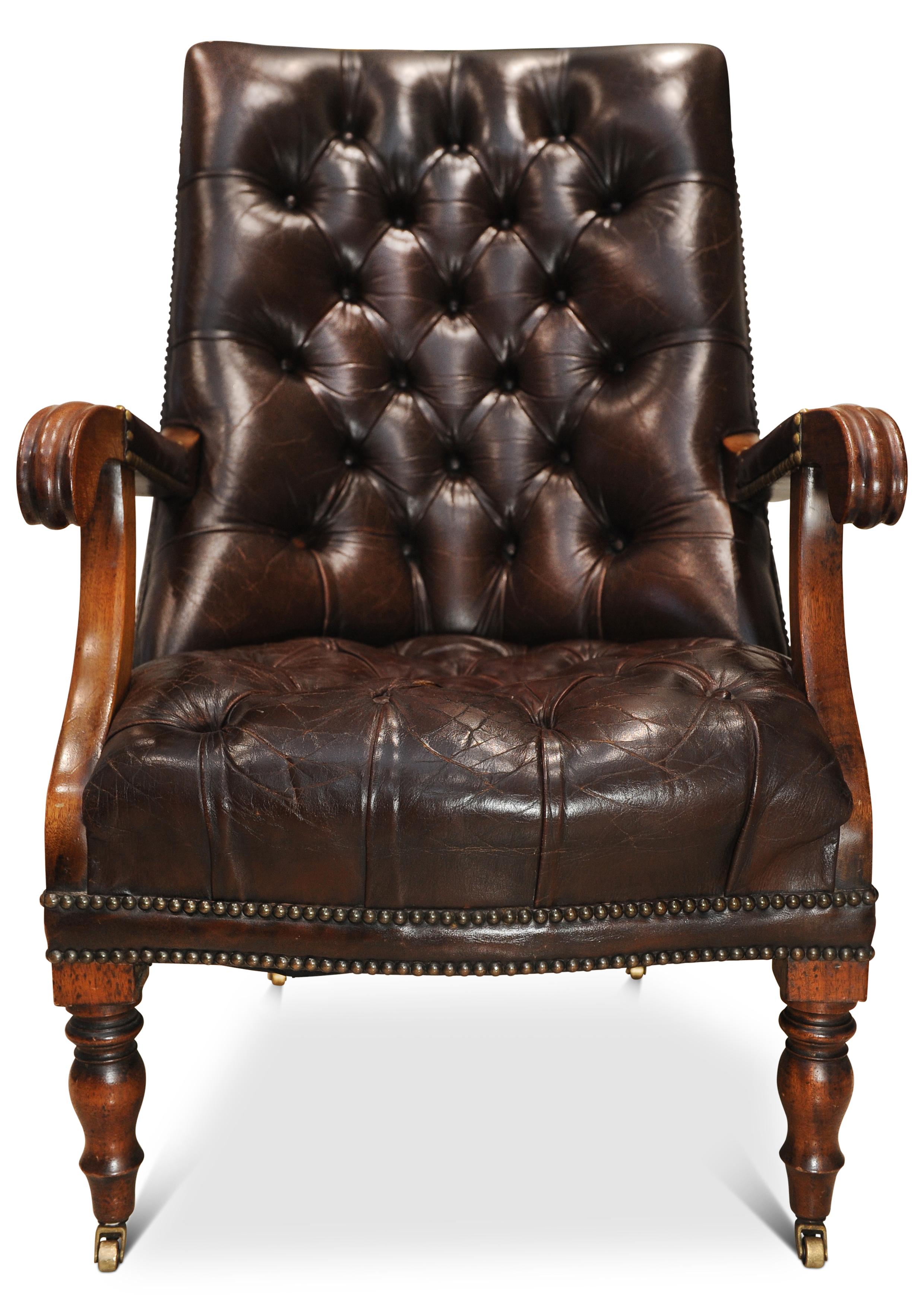 A British 1830's William IV polished antique brown leather chesterfield backed mahogany library armchair with brass stud detailing on brass castors.


.