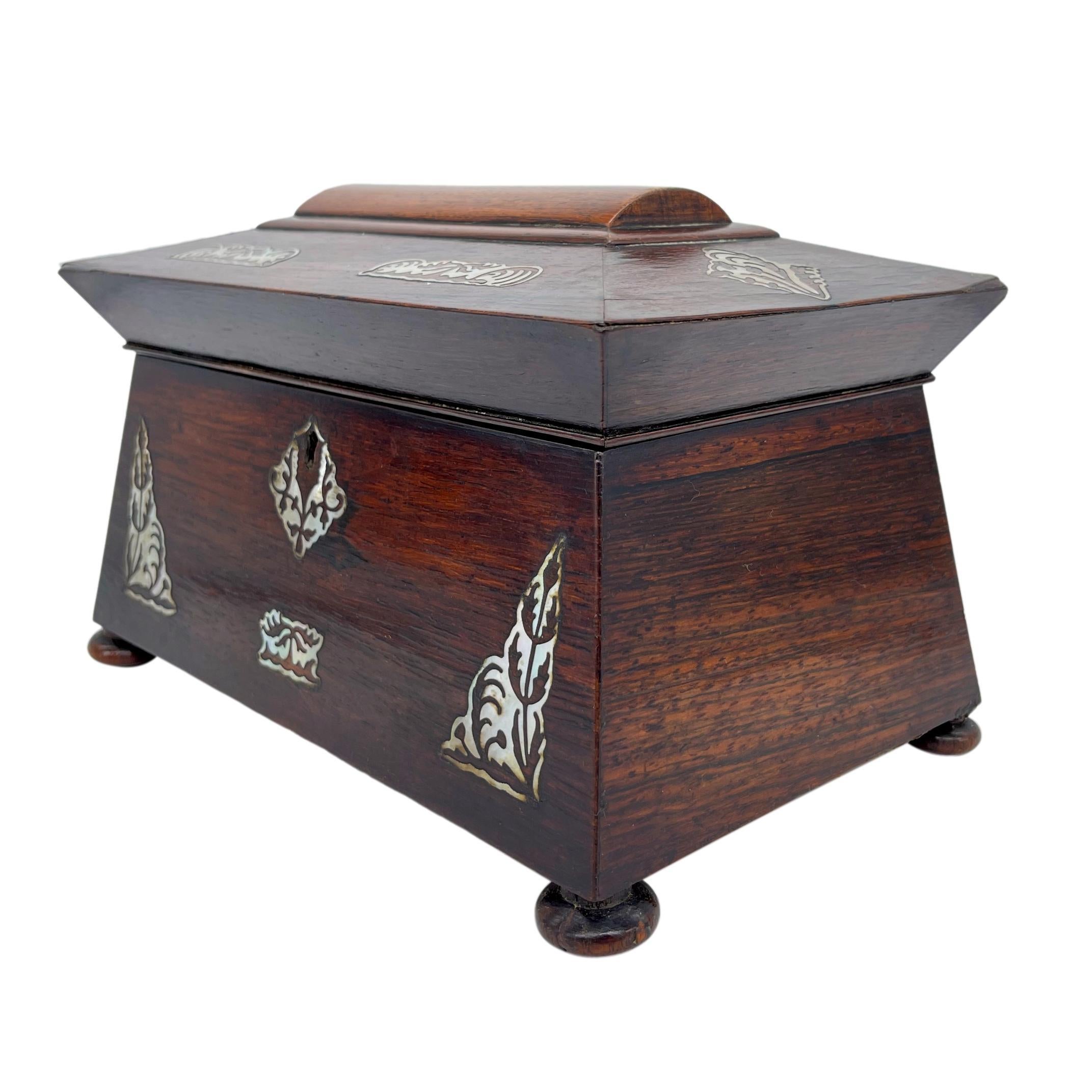 William IV rosewood tea caddy, of sarcophagus form with finely inlaid mother-of-pearl medallions with stylized acanthus leaves, the escutcheon plate with further similar decoration, the interior with both original chamfered solid rosewood