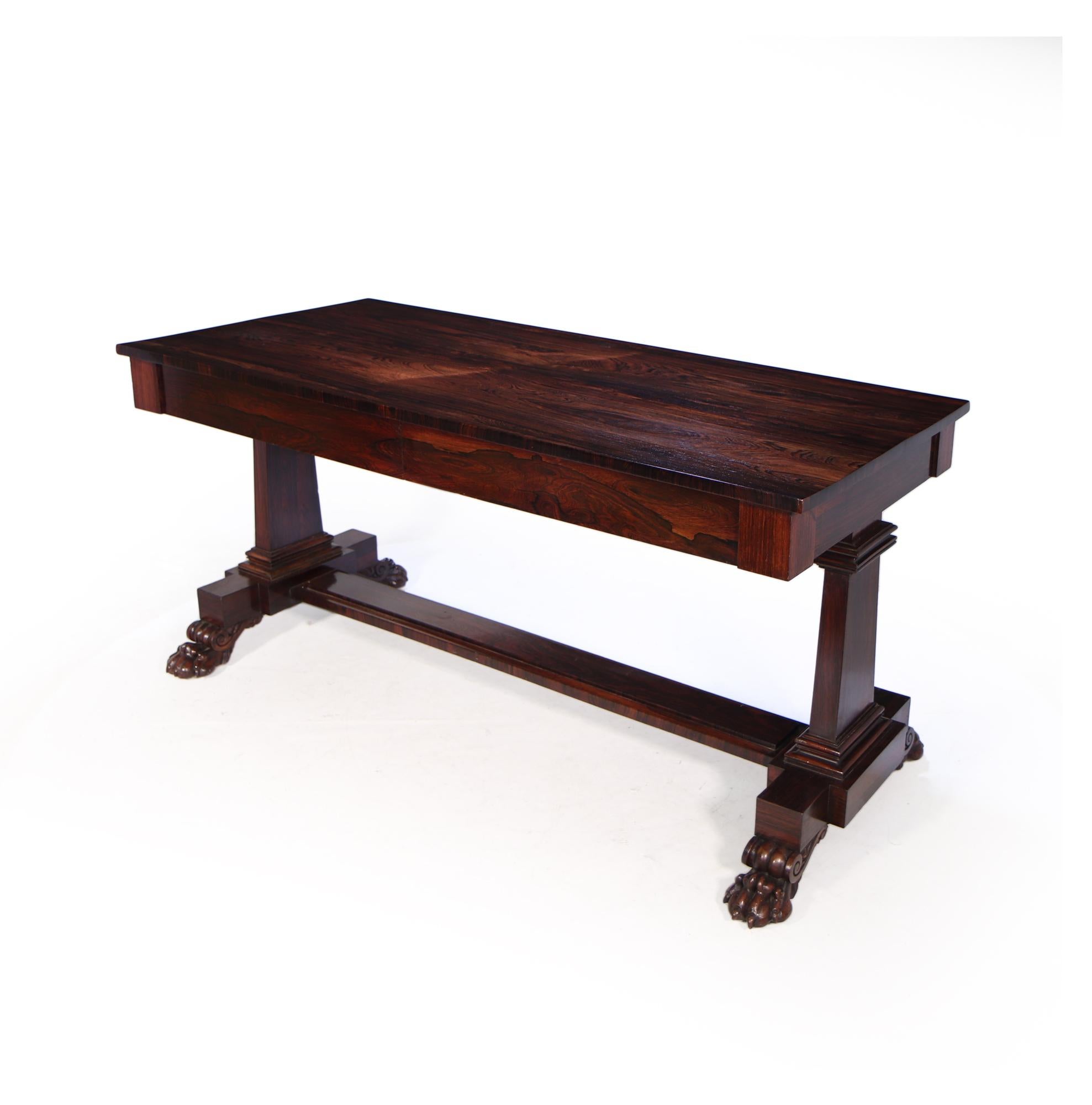 produced in England c1840 this highly figured rosewood library table has two blind freize drawers and stands on tapered square legs and terminates on exceptionally well carved ball and lion claw feet with fitted brass castors underneath, this