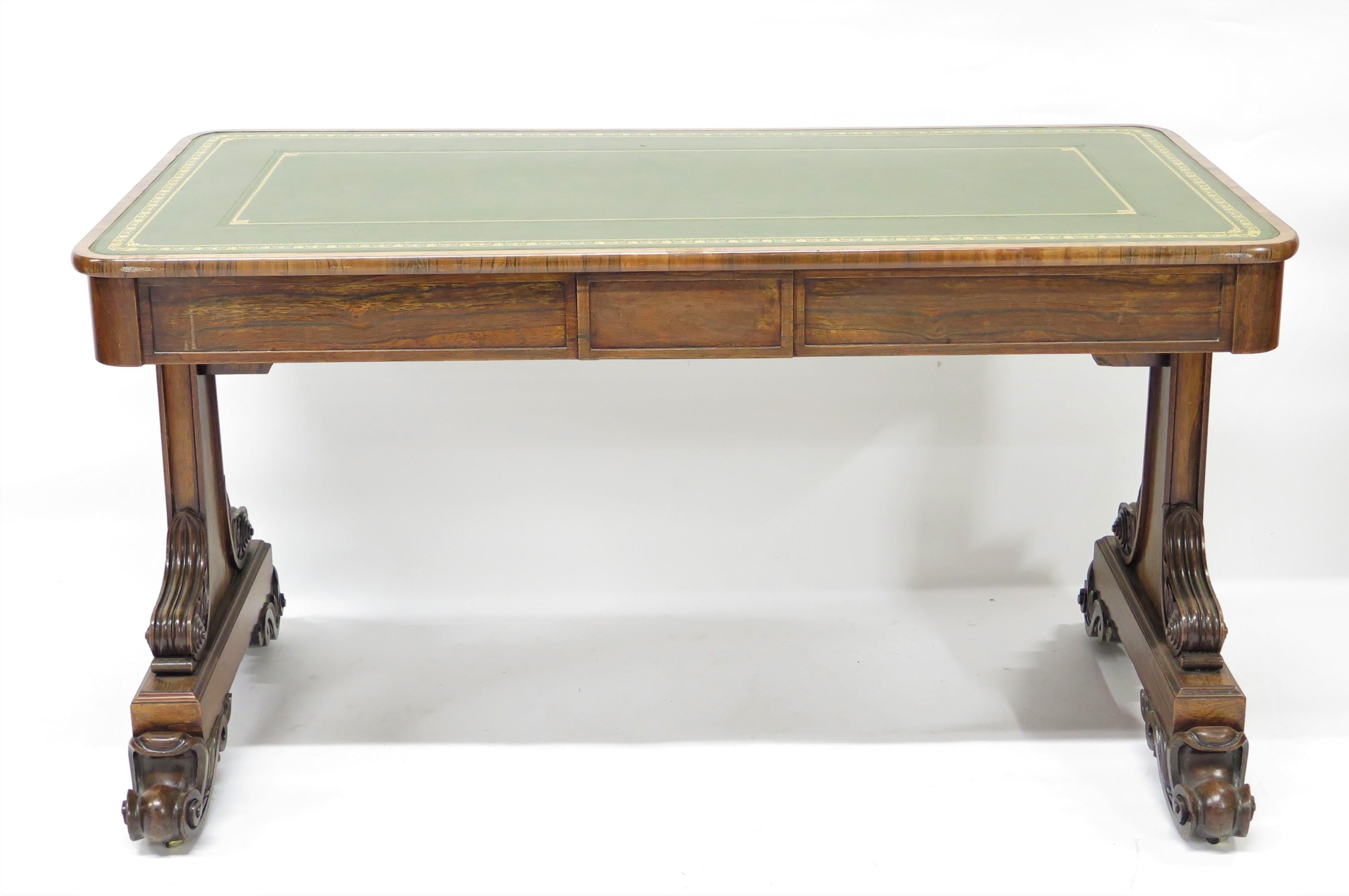 a William IV rosewood library table / writing desk with gilt embossed decoration and border on green leather work surface, two drawers on one side, the whole on castors, England, circa 1830s