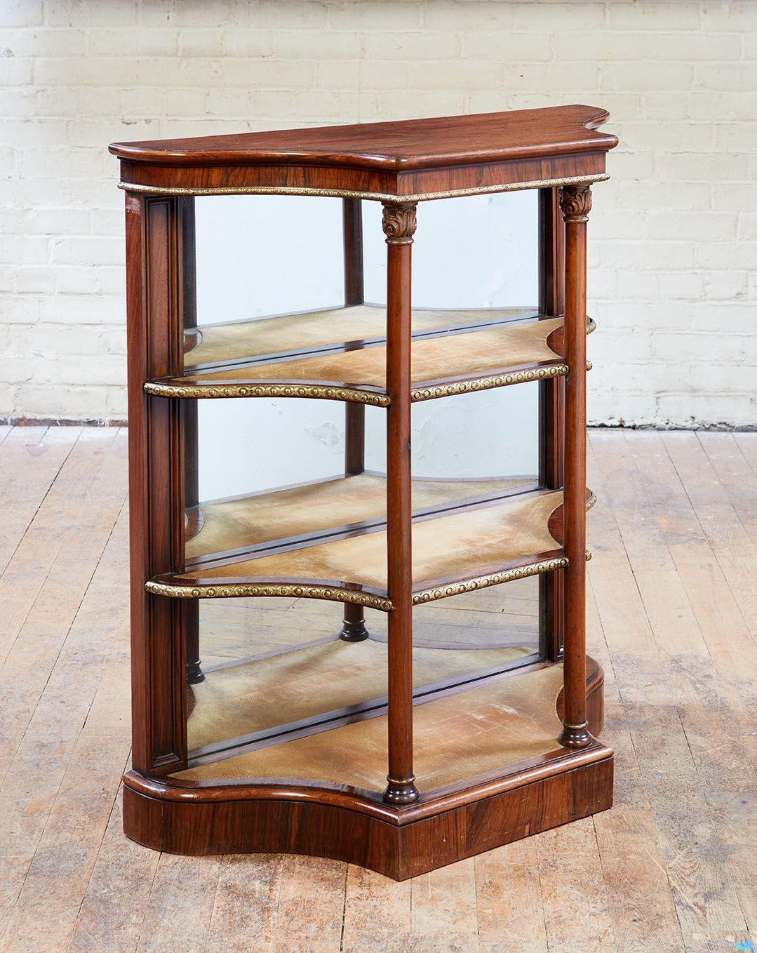 Fine William IV period rosewood four-tier mirrored etagere, the shaped top over apron with decorative brass trim over three suede lined shelves with mirrored back and supported by front columns, standing on plinth base.