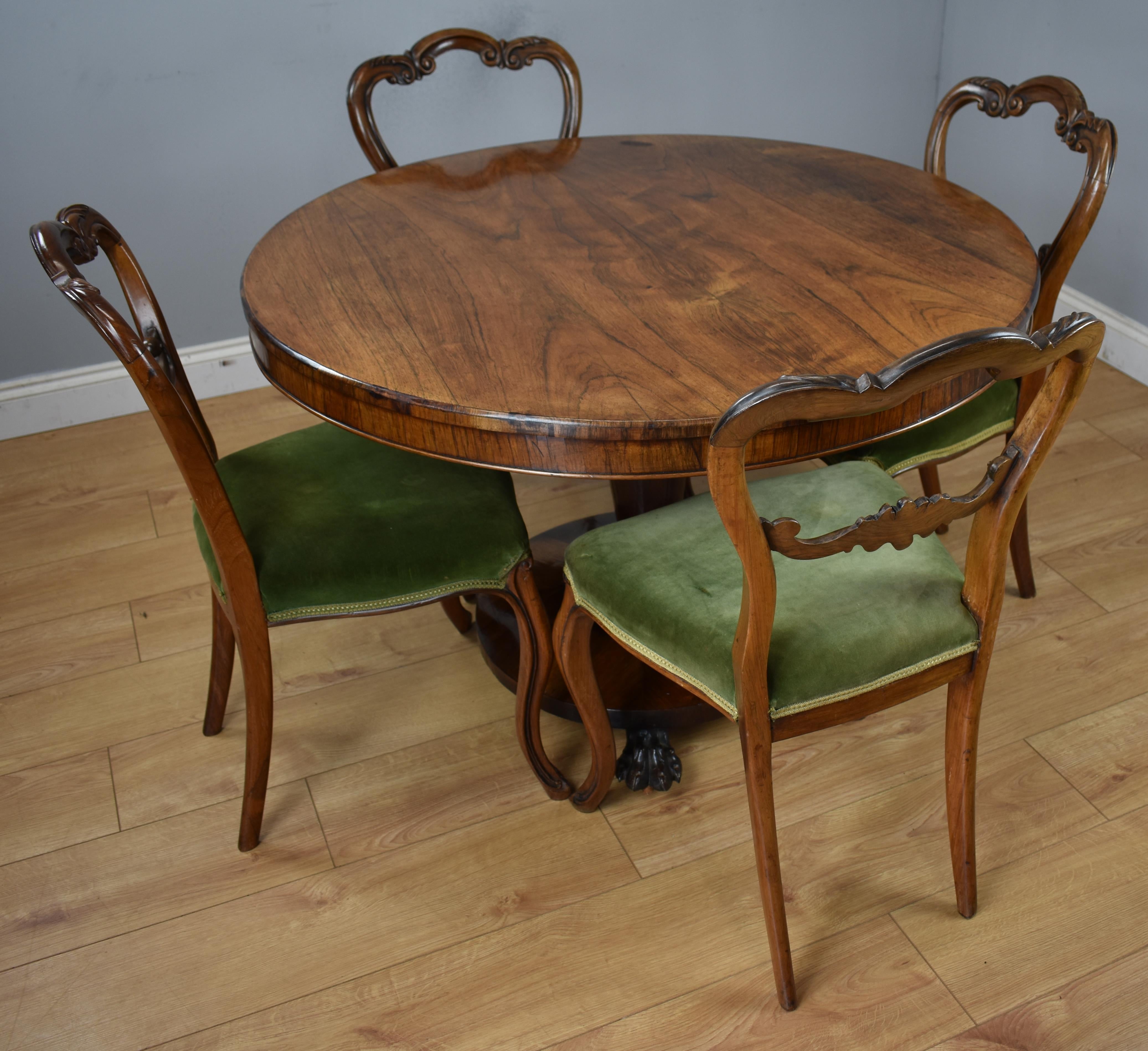 For sale is this William IV rosewood round tilt-top table and four rosewood chairs in good condition. The table has a nice figured rosewood top on a circular tapered pedestal on a circular base with paw feet on castors. The four rosewood chairs have